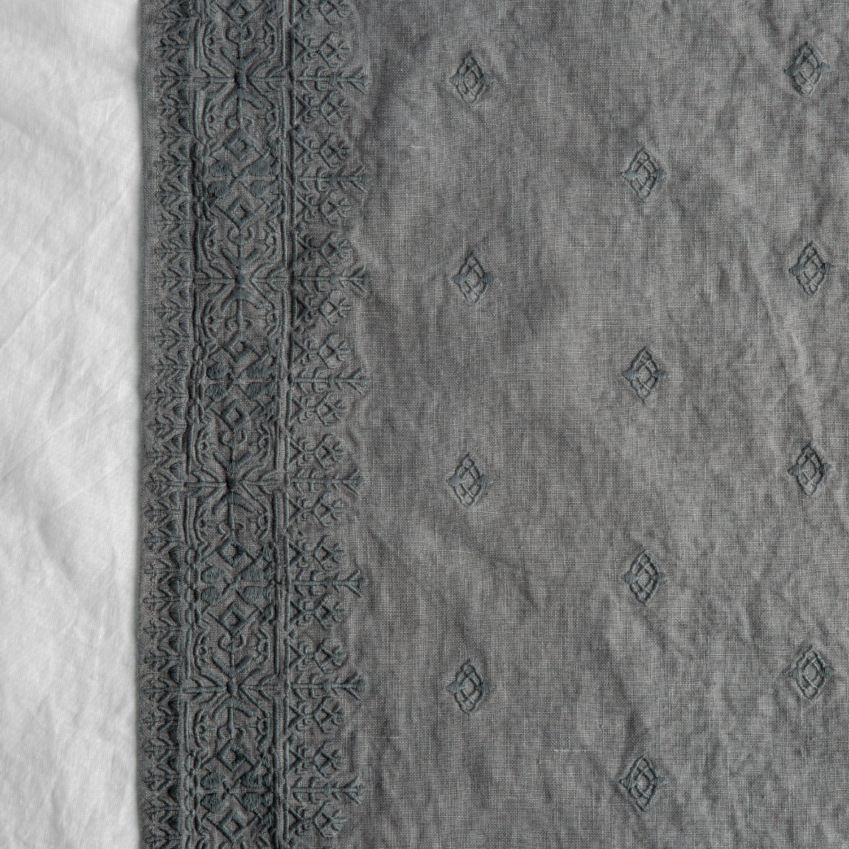 Moonlight: A close up of Ines, midweight linen with cotton embroidery, in moonlight, a saturated, cool, mid-dark grey tone.