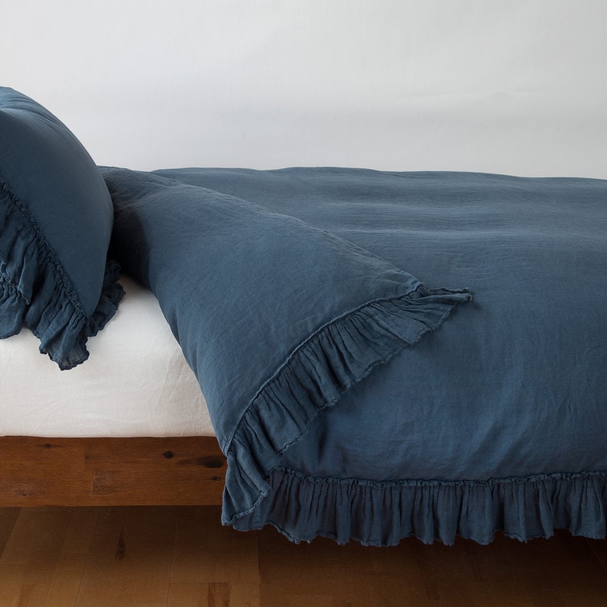 Midnight: duvet cover folded back over a white fitted sheet, shown with matching sham against a plain background - side view.