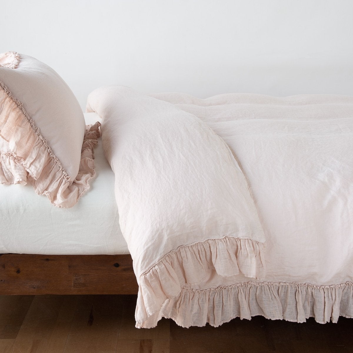 : Linen Whisper duvet cover folded back over a white fitted sheet, shown with matching sham against a plain background - pearl, side view.