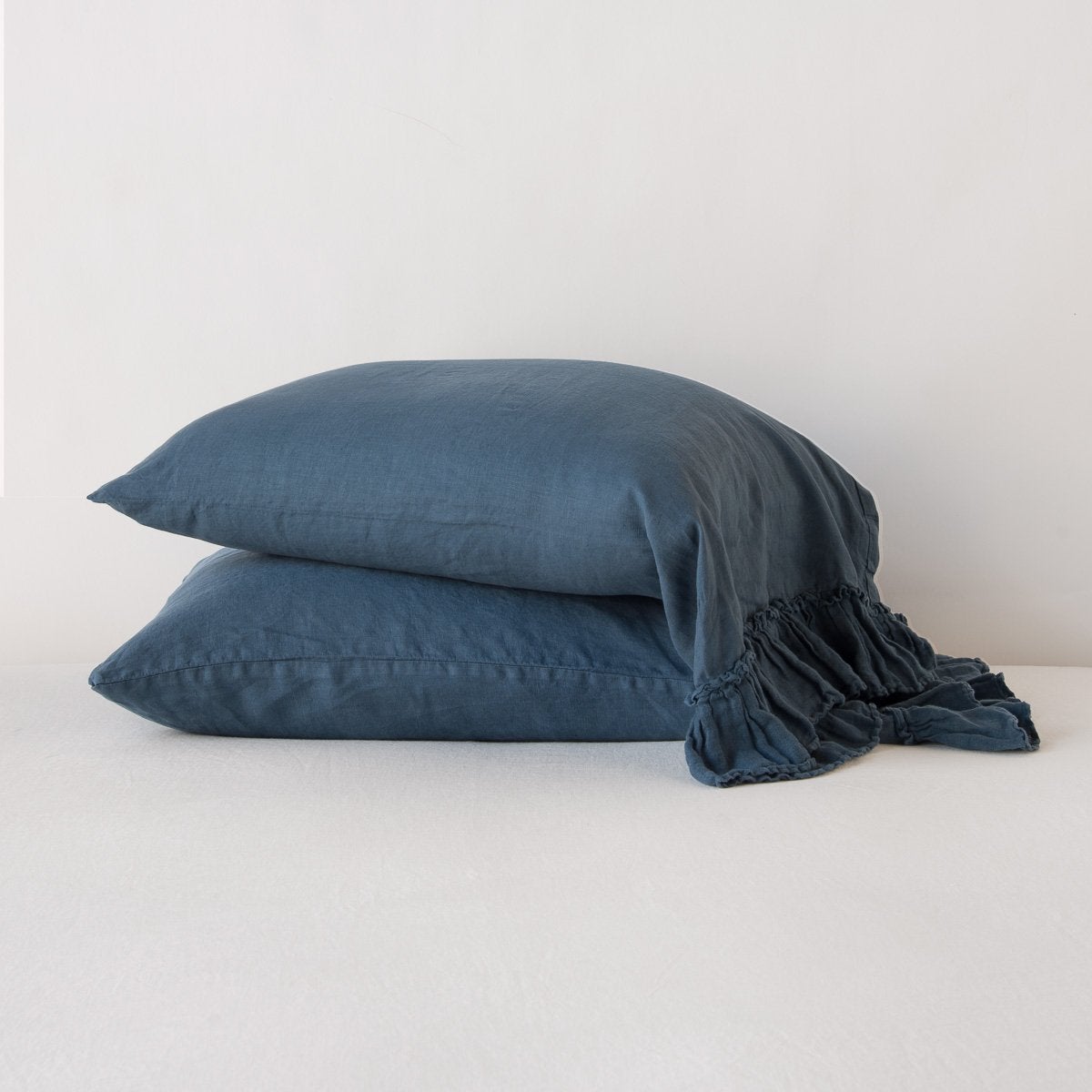Midnight: Two sleeping pillows stacked at a slight angle against a plain background, showcasing ruffle trim detail - side view.