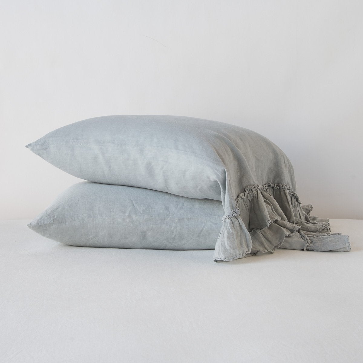 Mineral: Two sleeping pillows stacked at a slight angle against a plain background, showcasing ruffle trim detail - side view.