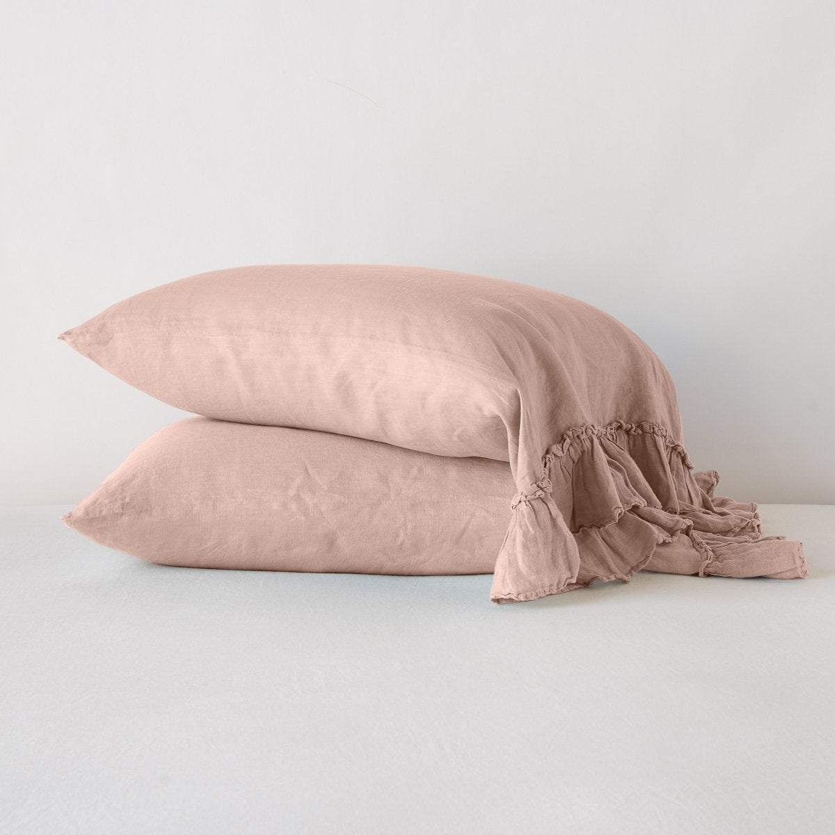 Rouge: Two sleeping pillows stacked at a slight angle against a plain background, showcasing ruffle trim detail - side view.