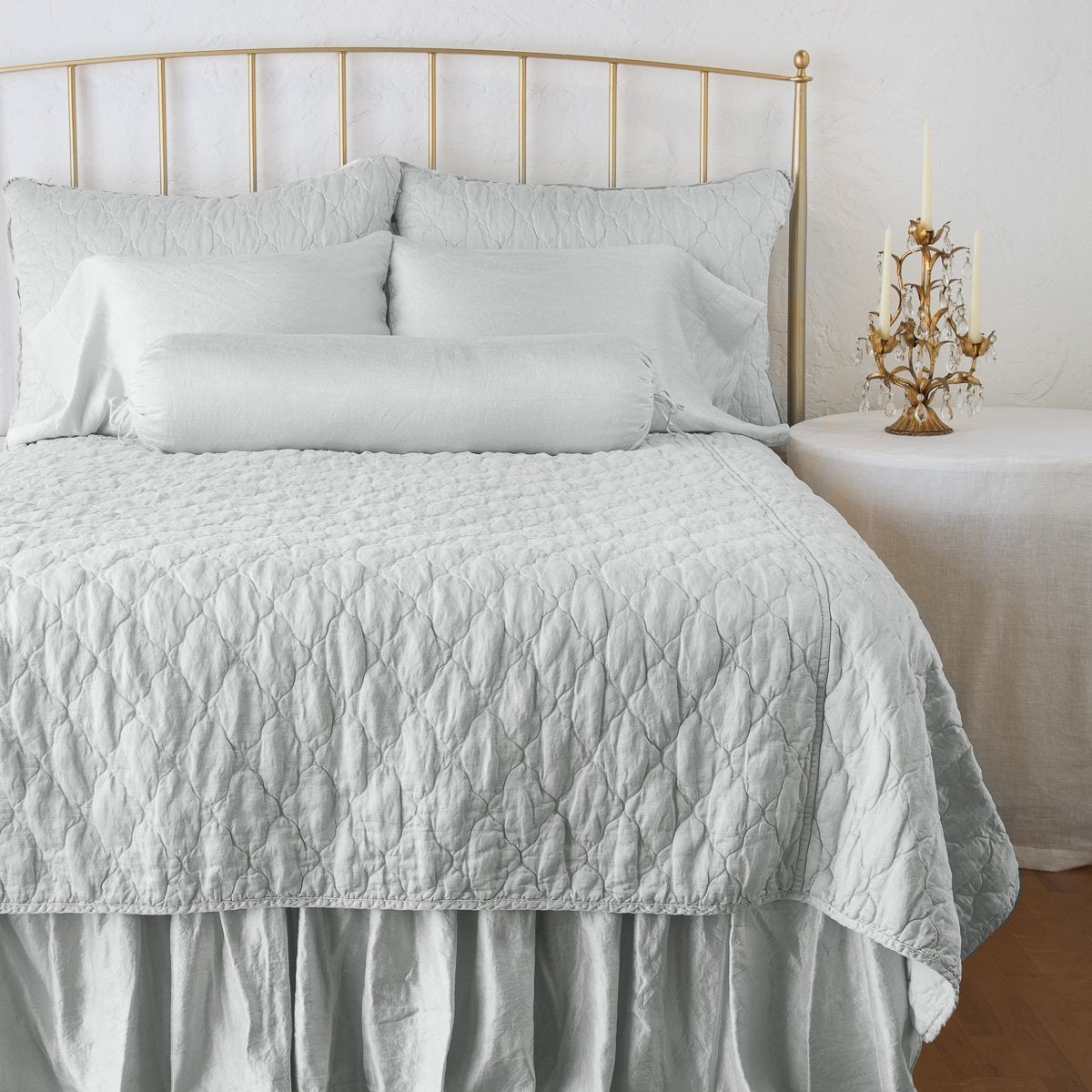 Cloud: coverlet on a shining, monochromatic bed with matching shams - end of bed view.