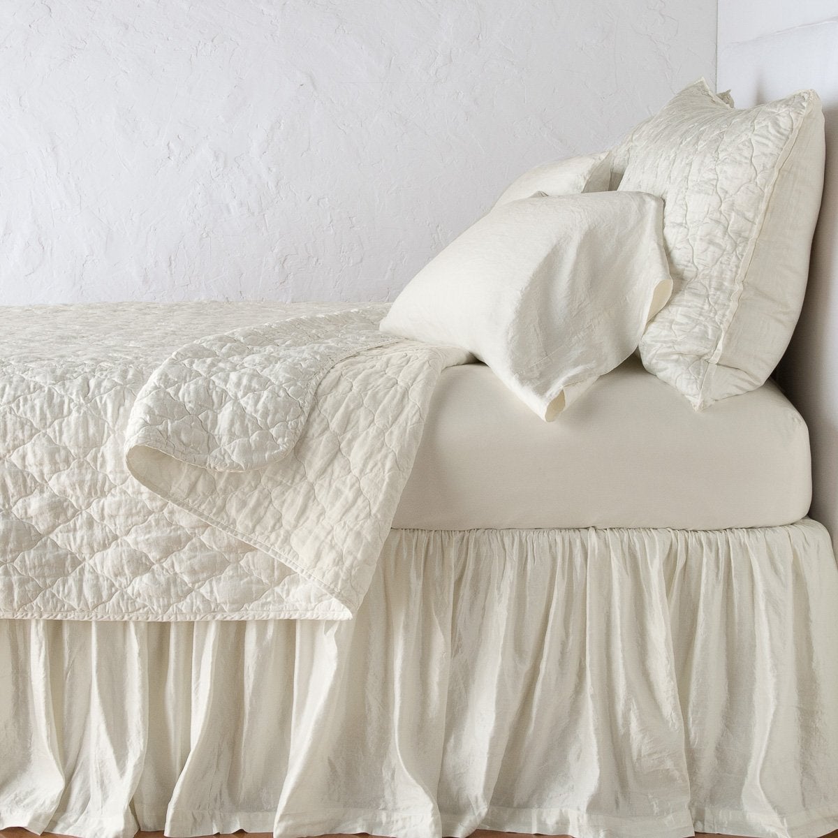 Parchment: coverlet neatly folded back to reveal linen reverse, on a monochromatic bed - side view.