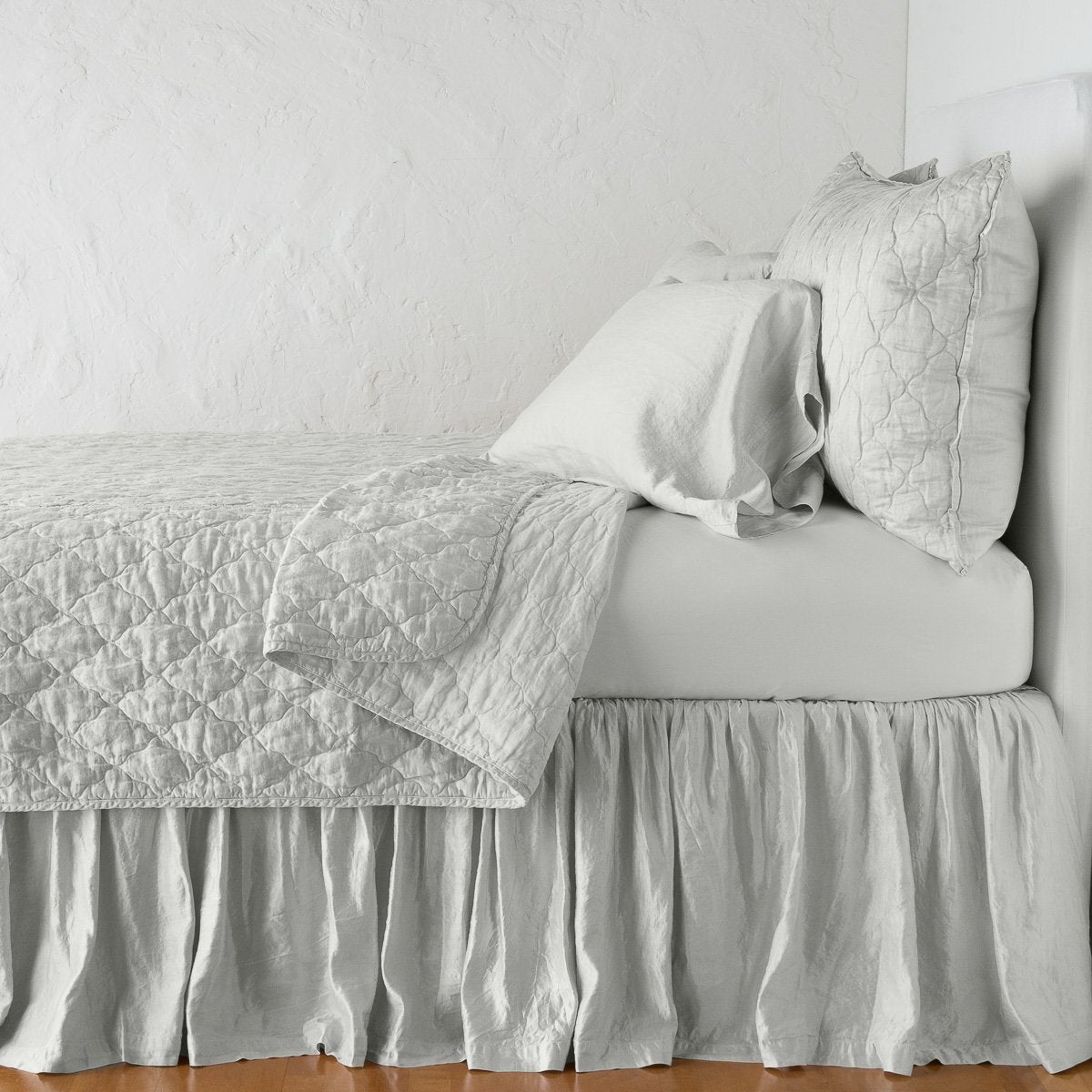 Sterling: coverlet neatly folded back to reveal linen reverse, on a monochromatic bed - side view.