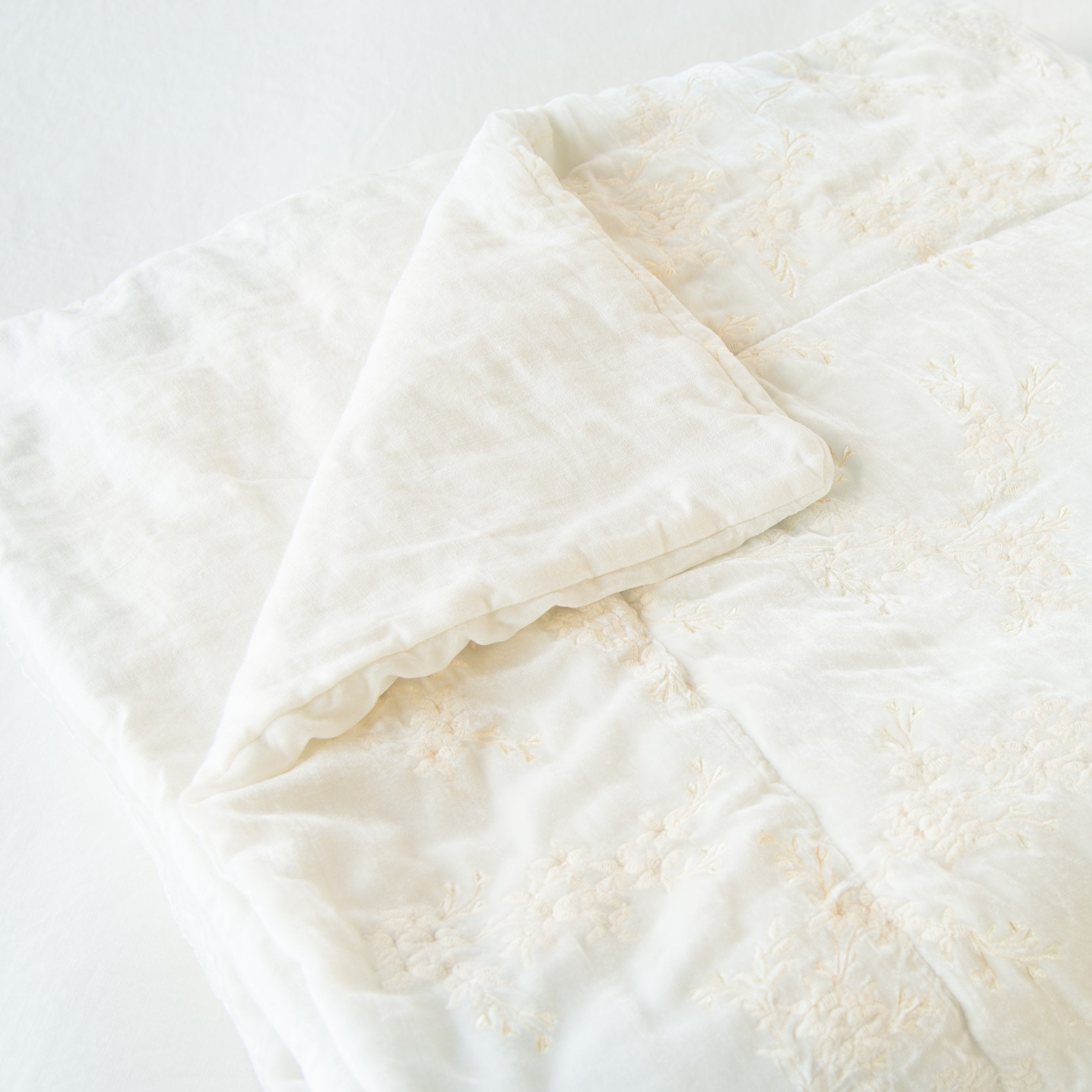 Winter White: Close up of blanket neatly folded on a light background, with a corner turned back to showcase the linen back - slight overhead angle.