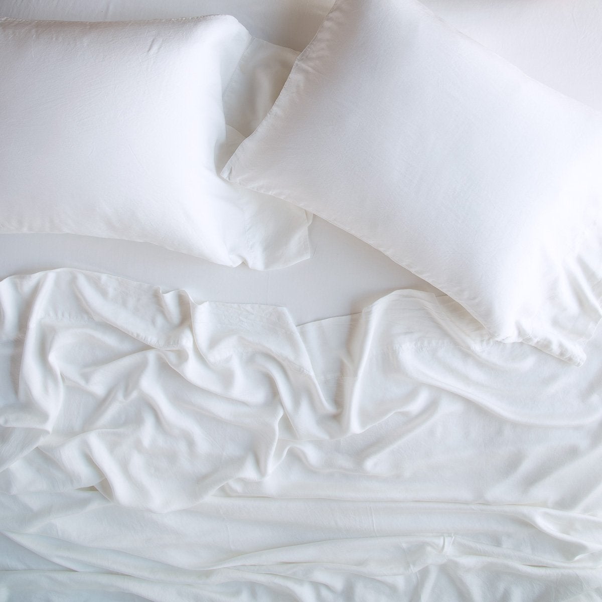 White: rumpled sheeting and sleeping pillows - overhead view.