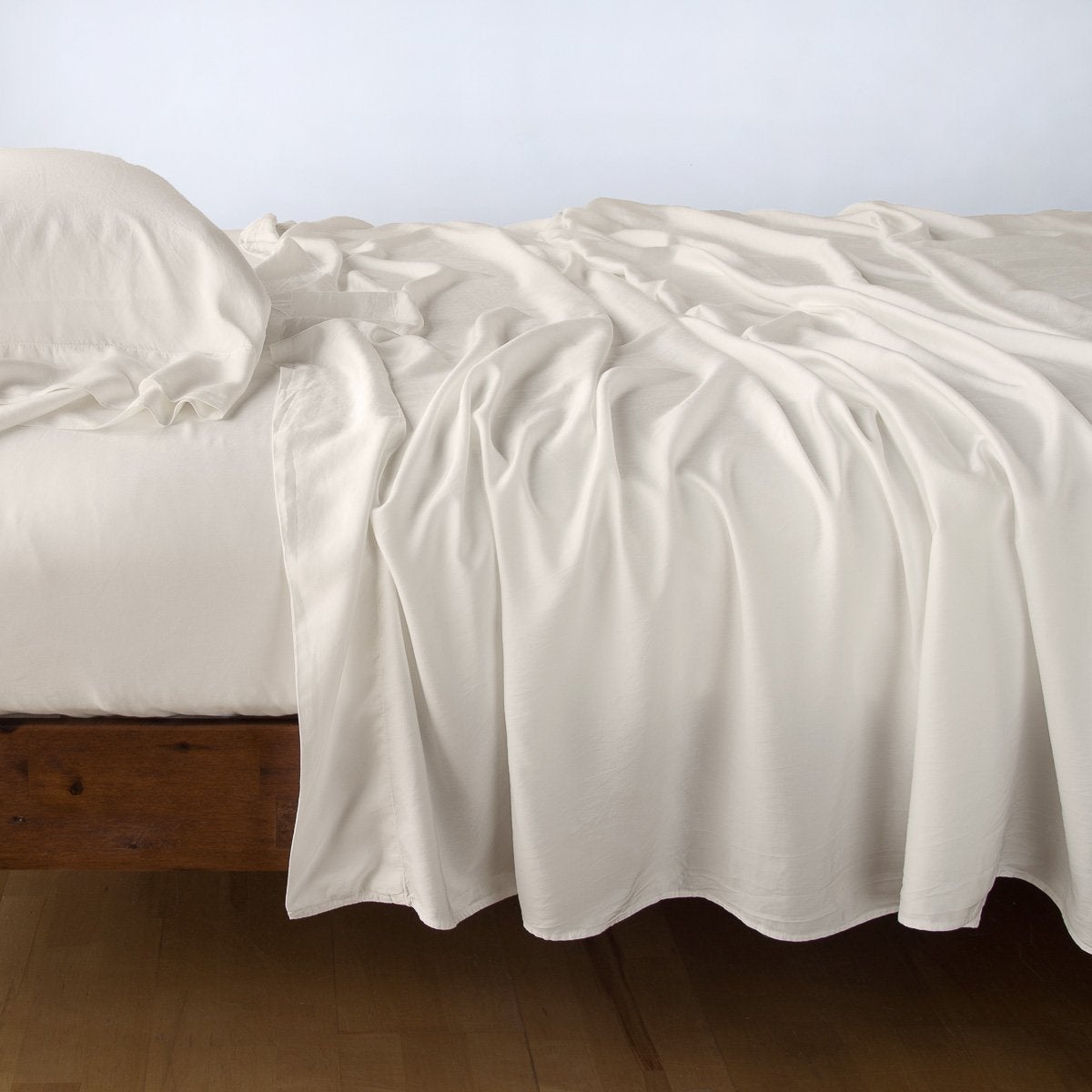 Parchment: Rumpled flat sheet with matching fitted sheet and sleeping pillow - side view.