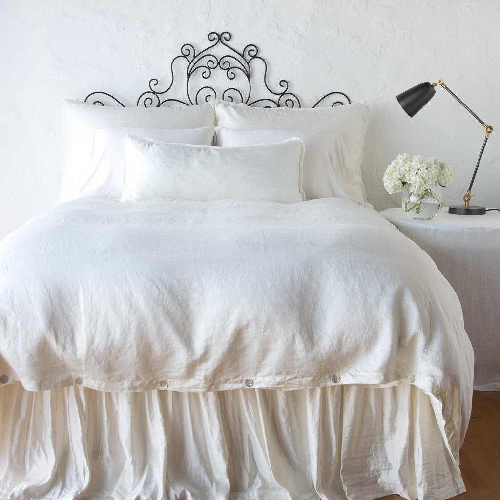 : Paloma duvet cover with matching pillows and bed skirt - winter white, end of bed view.