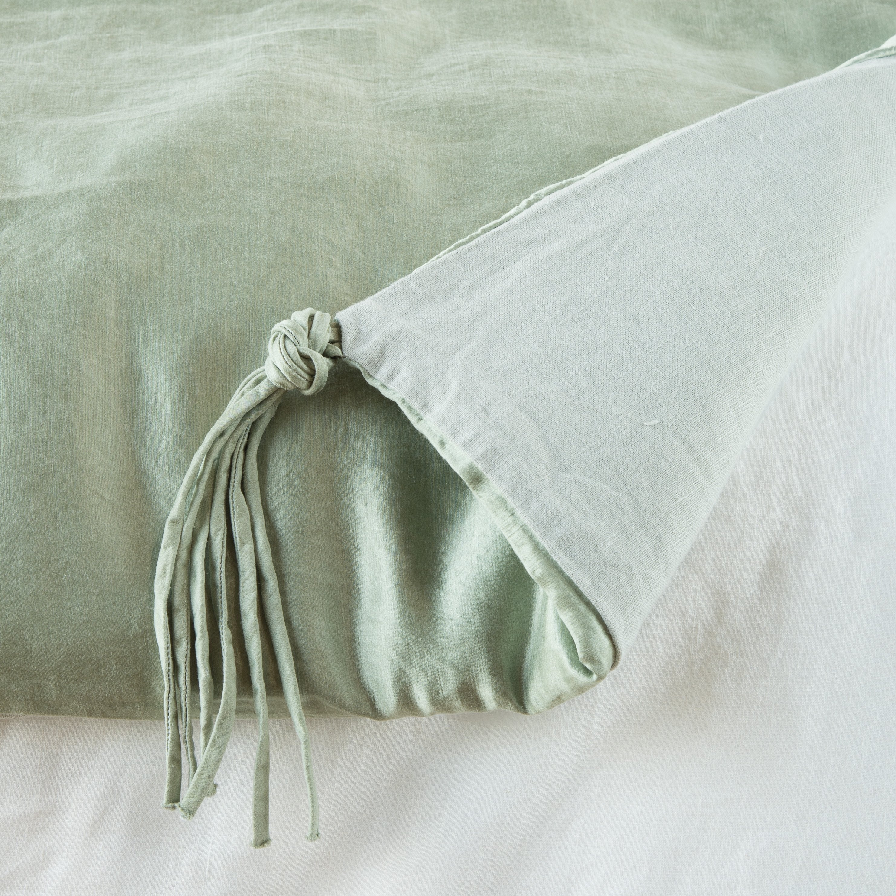 Eucalyptus: Close up of blanket, with a corner turned back to showcase the midweight linen back and corner tassel - overhead view.