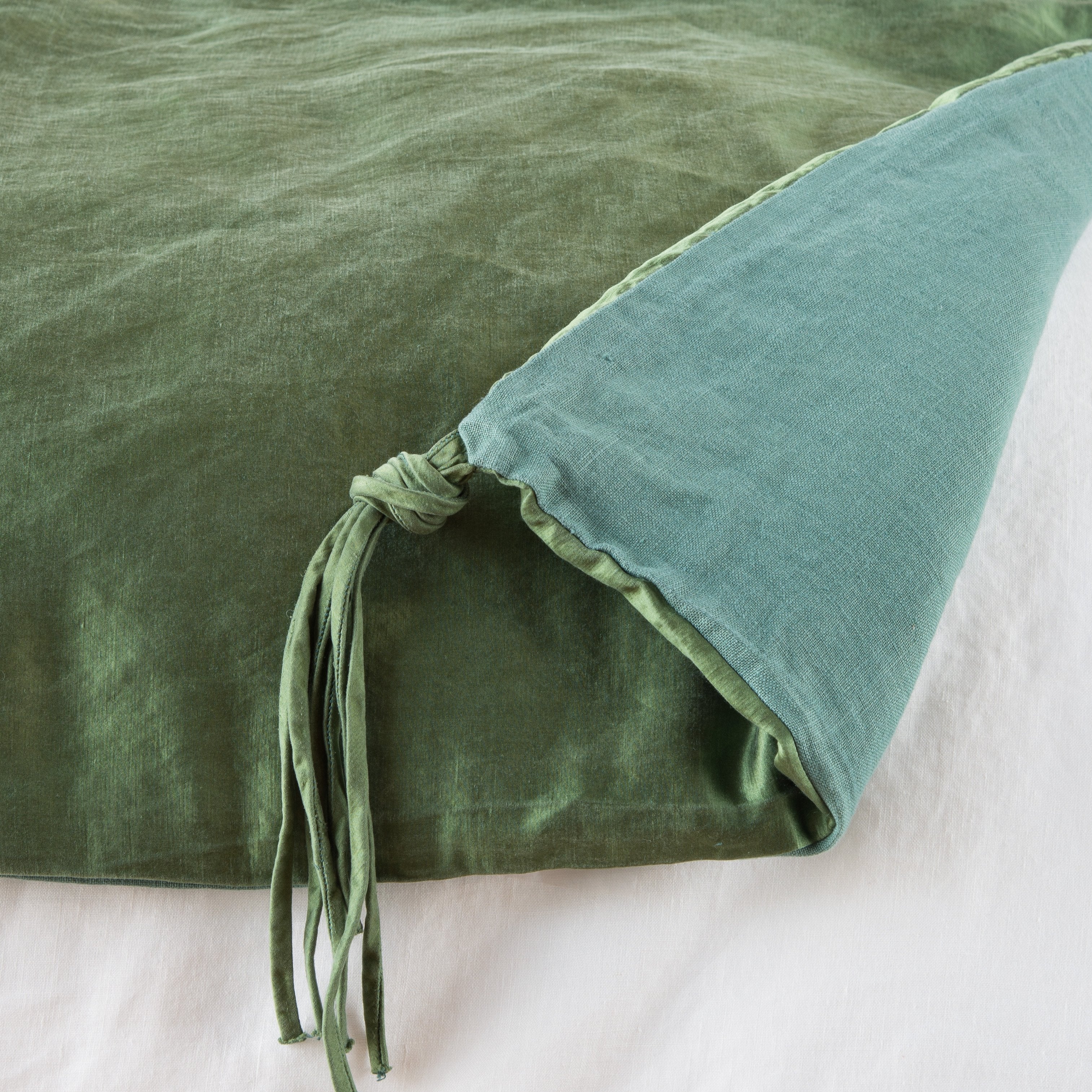Jade: Close up of blanket, with a corner turned back to showcase the midweight linen back and corner tassel - overhead view.