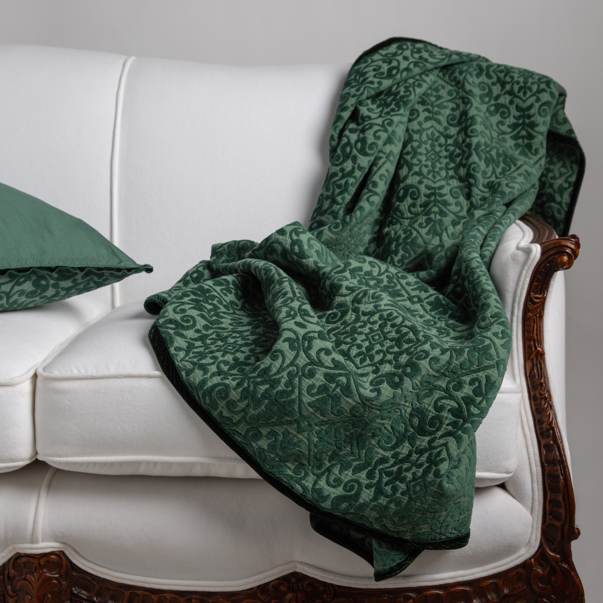 : Matching pillow and vienna throw blanket in jade on white couch and white background.