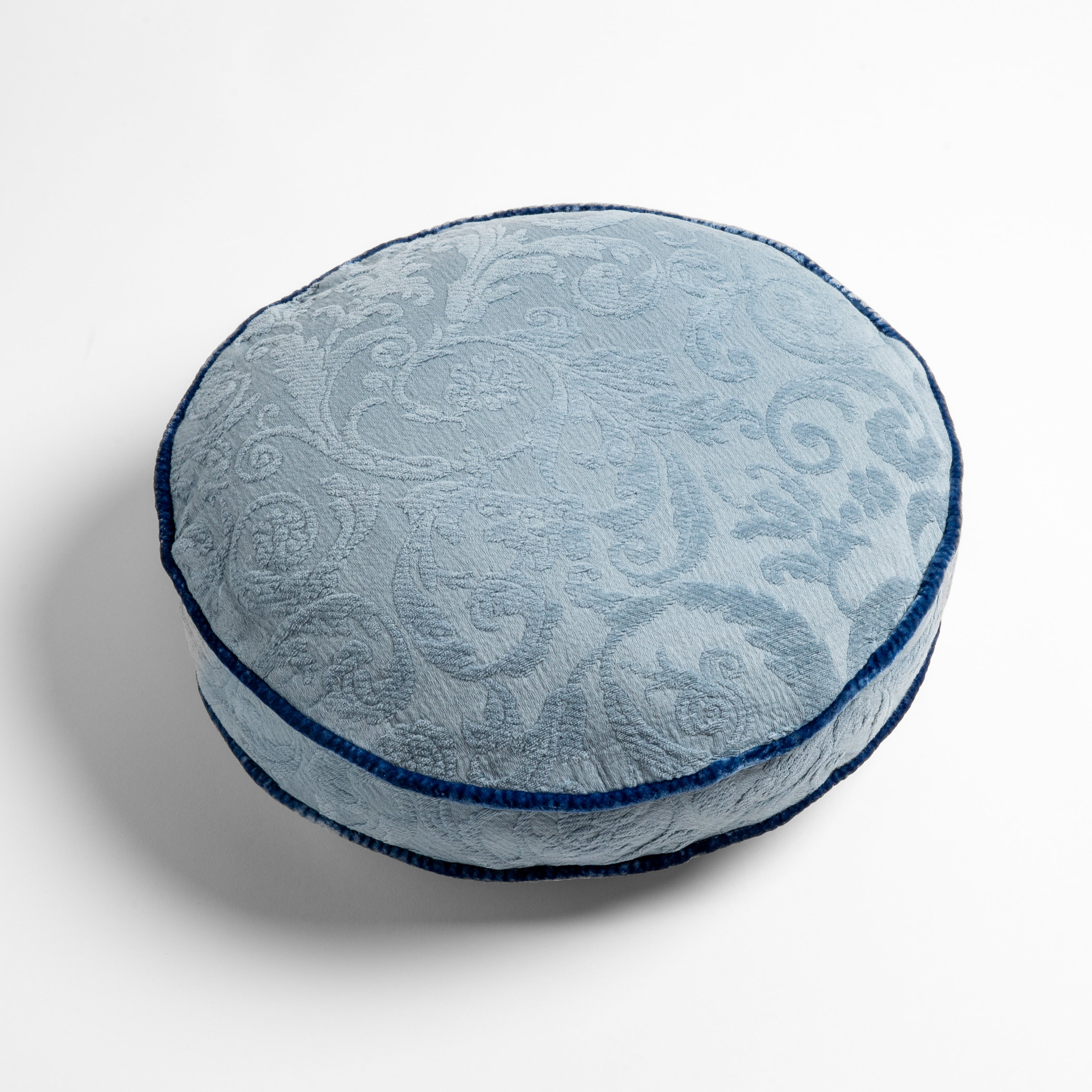 Tahoe Blue: Organic cotton damask round pillow with silk velvet trim on white background — overhead angle.
