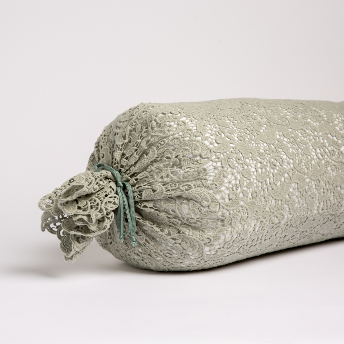 Eucalyptus: one end of a lace boslter cover on a winter white liner against a white background. 