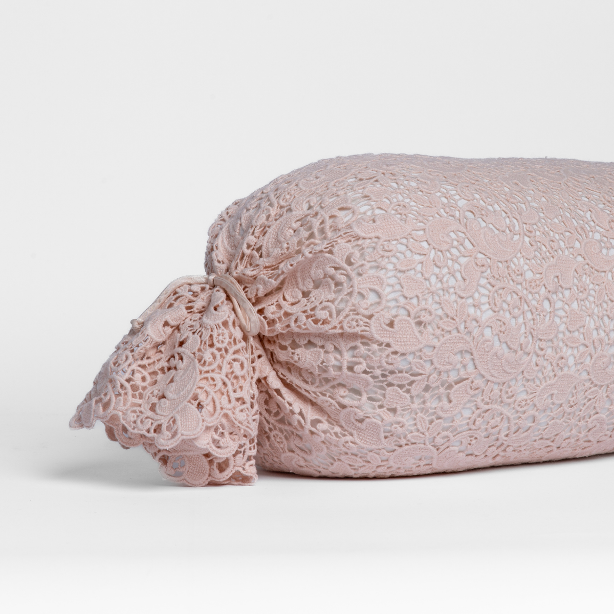 Pearl:  one end of a lace boslter cover on a winter white liner against a white background. 