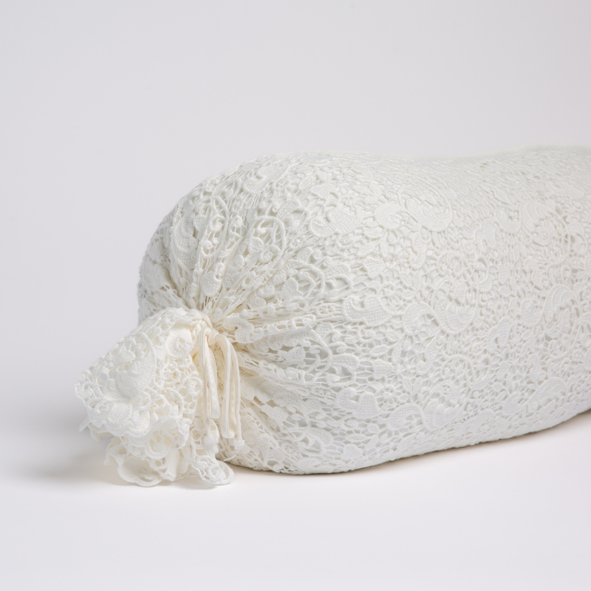 Winter White:  one end of a lace boslter cover on a winter white liner against a white background. 
