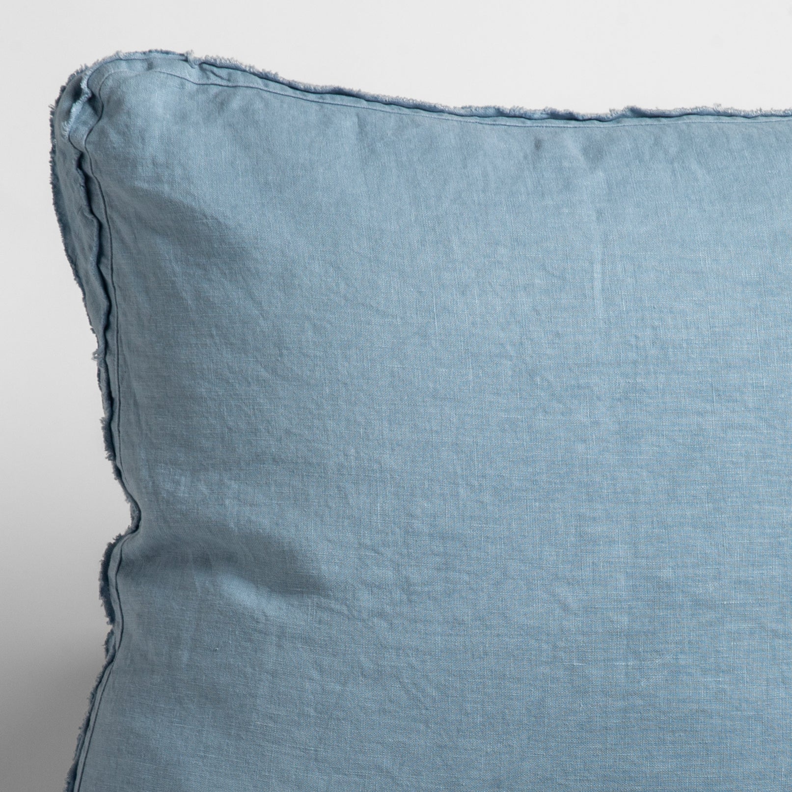 Tahoe Blue: close up of midweight linen pillow corner with raw edges trimming its gusset. 