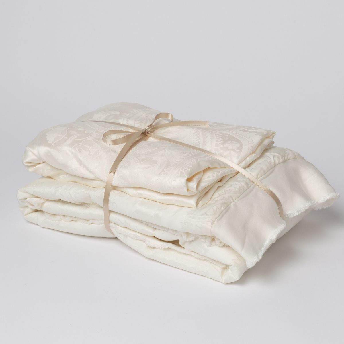 Winter White:  matching crib sheet and baby blanket bundled and tied with a ribbon against a white background.