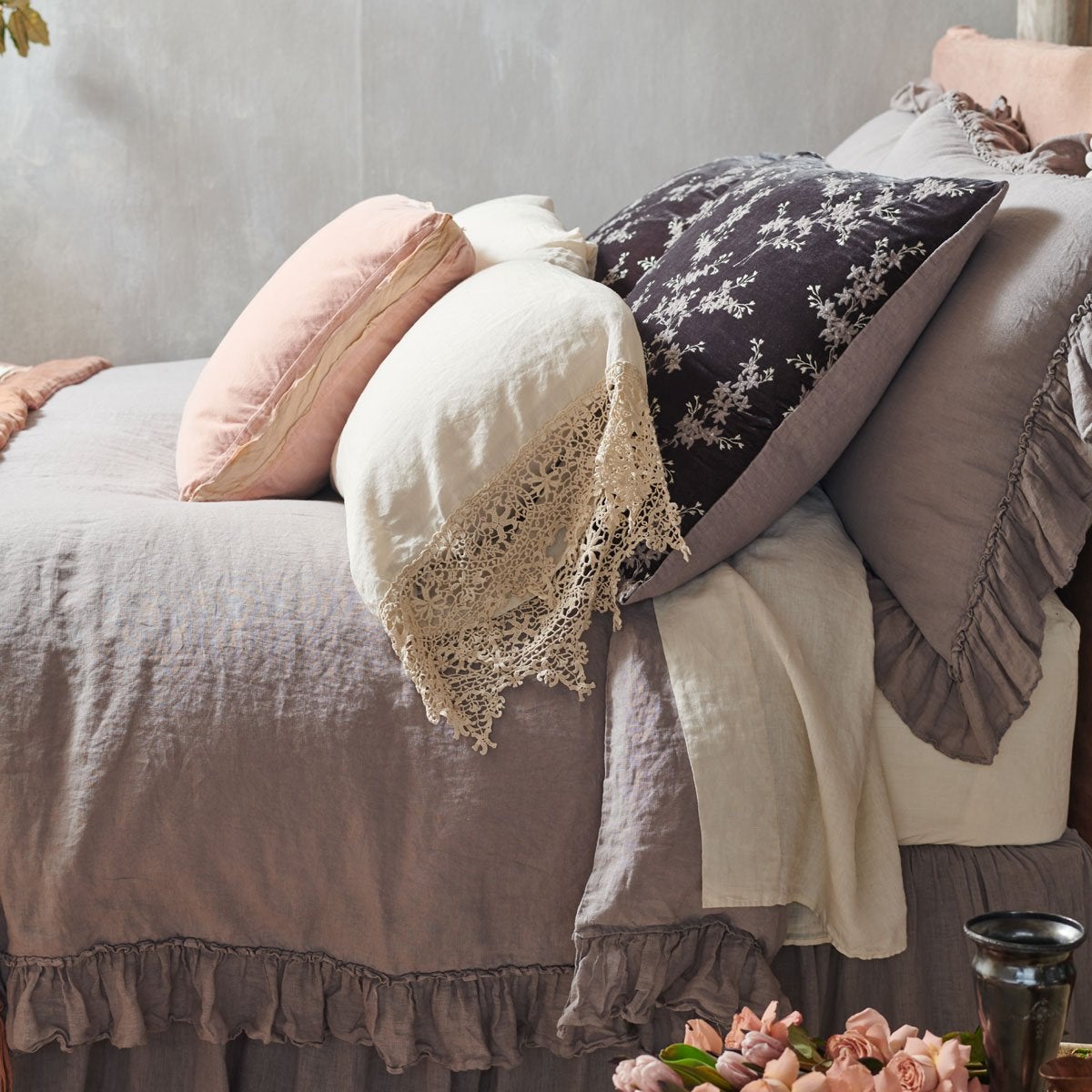 [allvariants]: Lynette sham in rich moonlight adds elegance and luxury to a linen bed embellished with ruffles and cotton lace - cropped side view. 