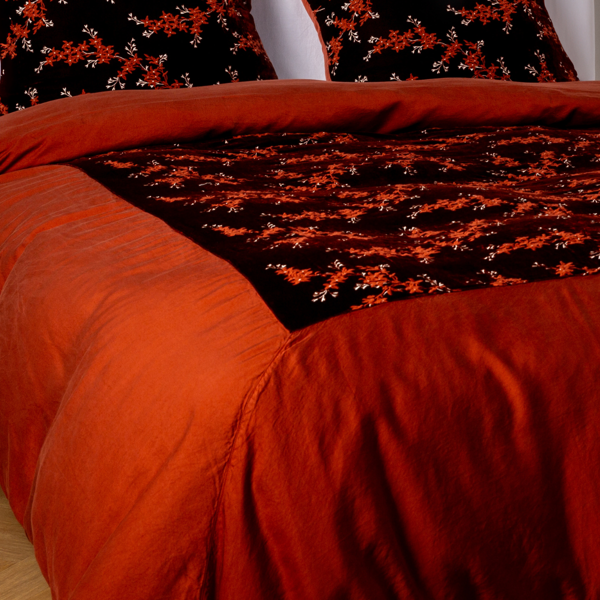 Autumn: A close-up of the mitered corner of an embroidered silk velvet and tencel duvet cover — its matching shams barely visible in the shot. 