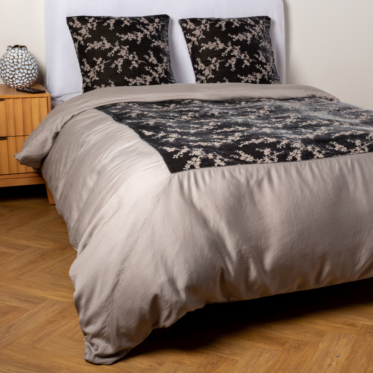 Fog: A ¾ angle shot of an embroidered silk velvet and tencel duvet cover and matching shams with a vase and cell phone on the side table. 