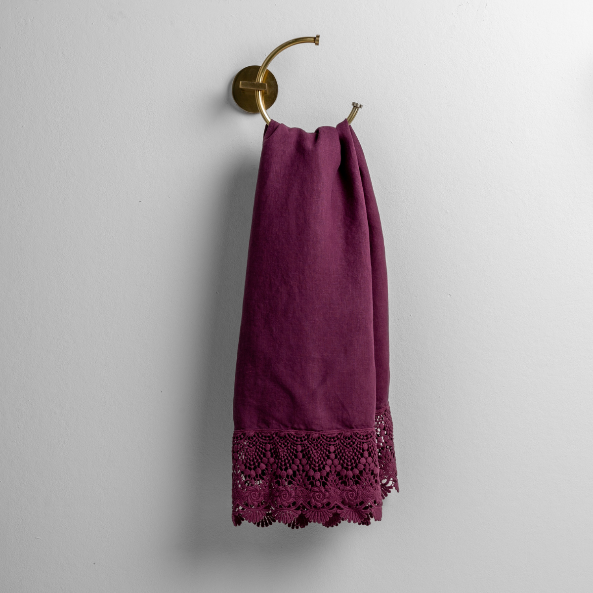 Fig: linen with mattine lace trimmed guest towel on a decorative towel ring mounted on a white wall. 