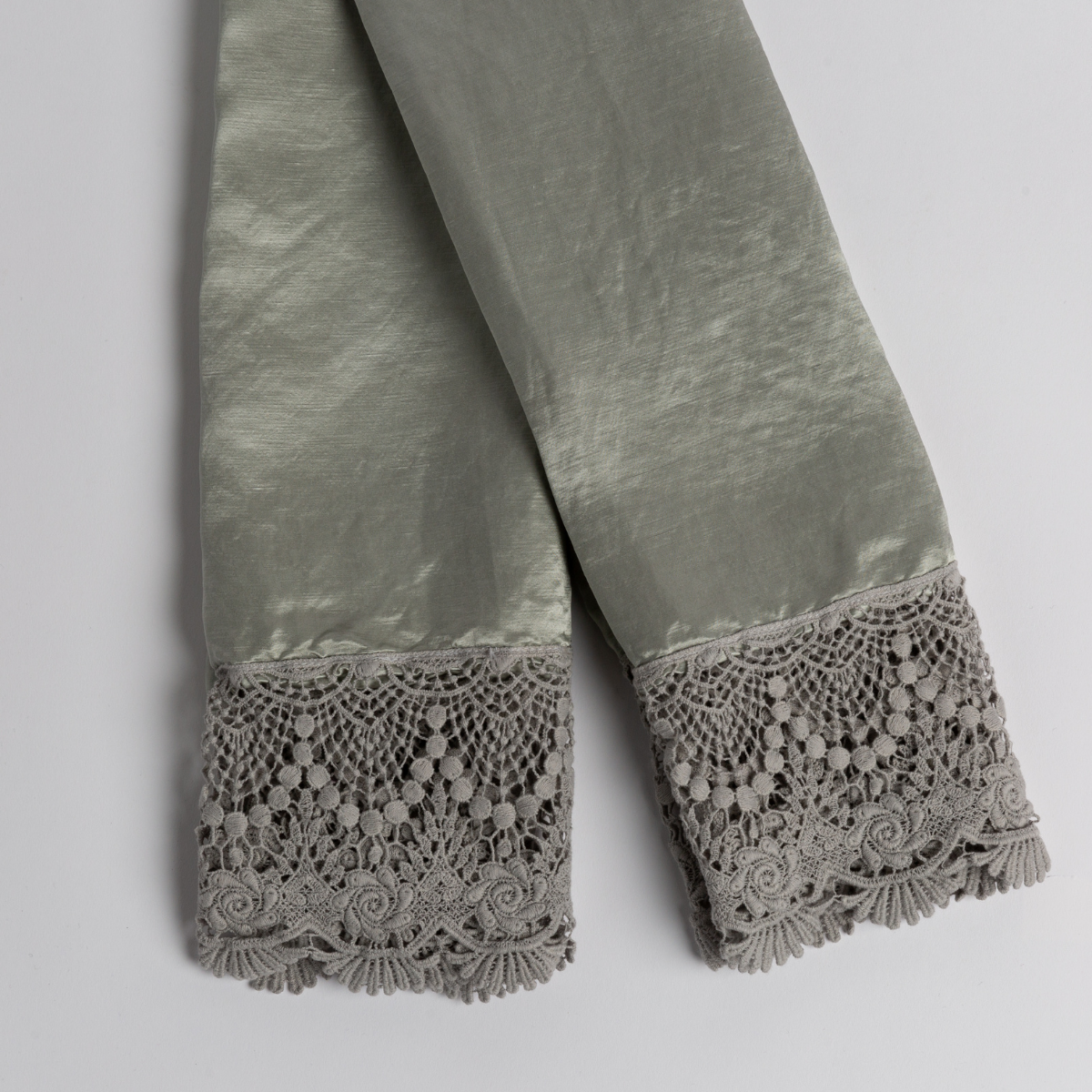 A pair of folded lace trimmed charmeuse pillowcases shot from overhead against a white background. 