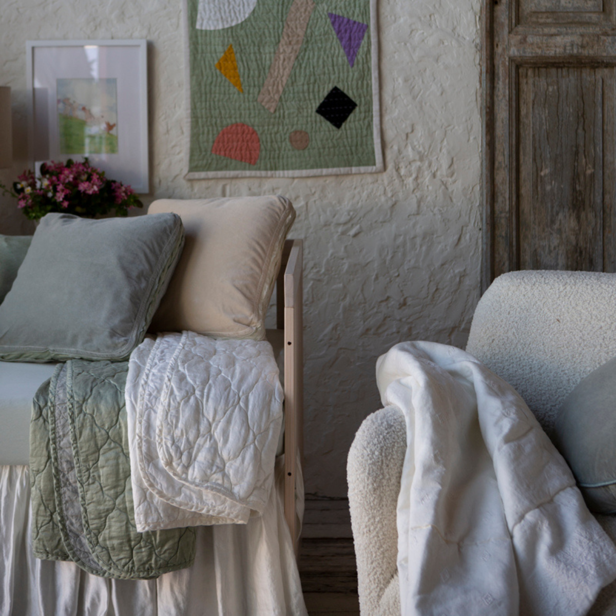 [allvariants]: Close up of blankets in winter white and eucalyptus, folded over the front of a crib in a tonal nursery scene.