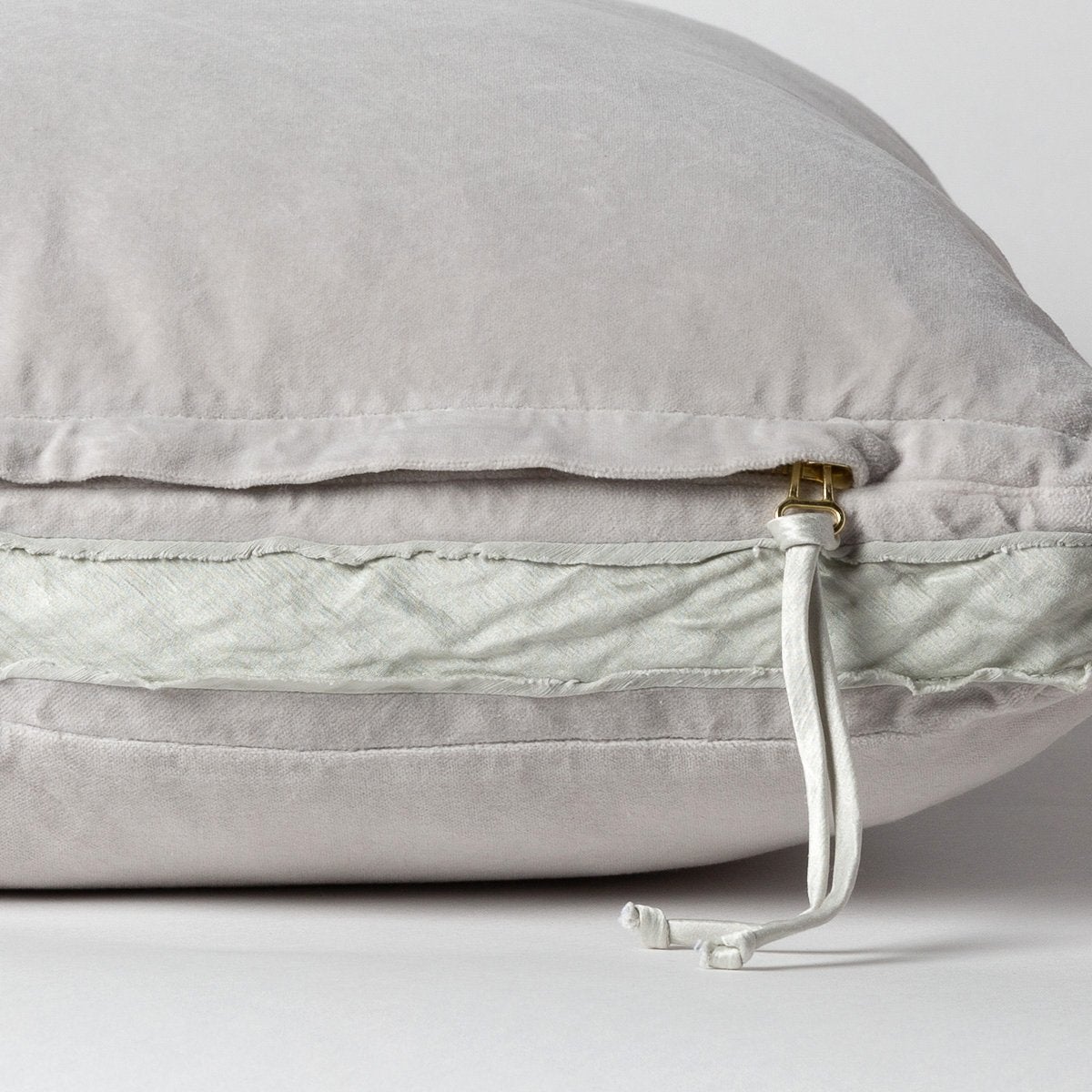 Sterling: Close-up of charmeuse gusset, raw-edge trim, and brass zipper detail  on cotton velvet sham - side view.