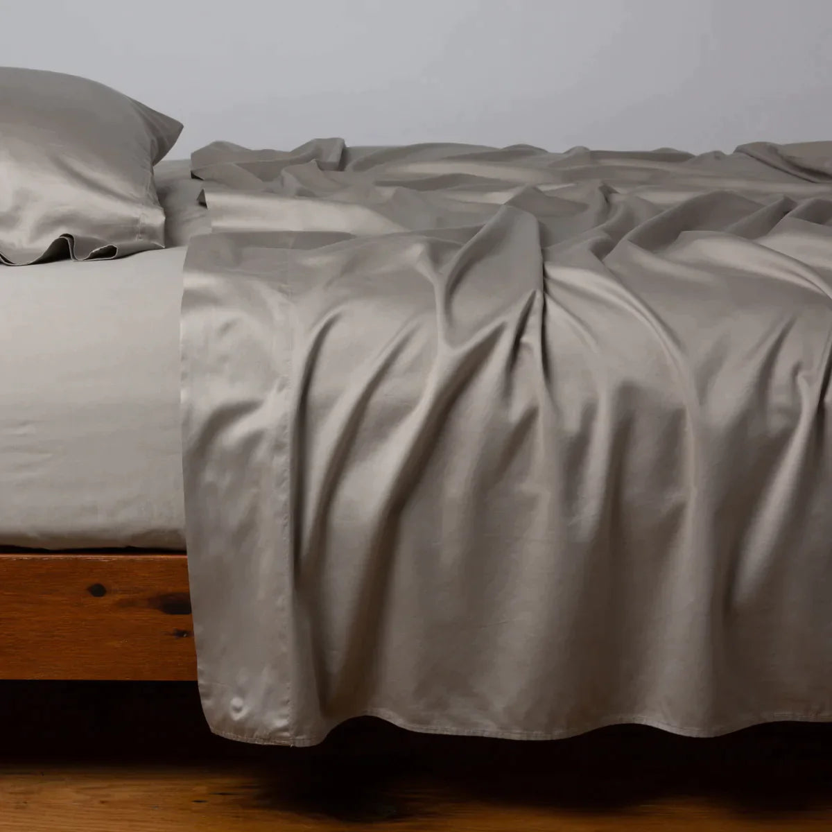 Fog: Cotton sateen flat sheet, shown with matching fitted sheet and sleeping pillow - side view.