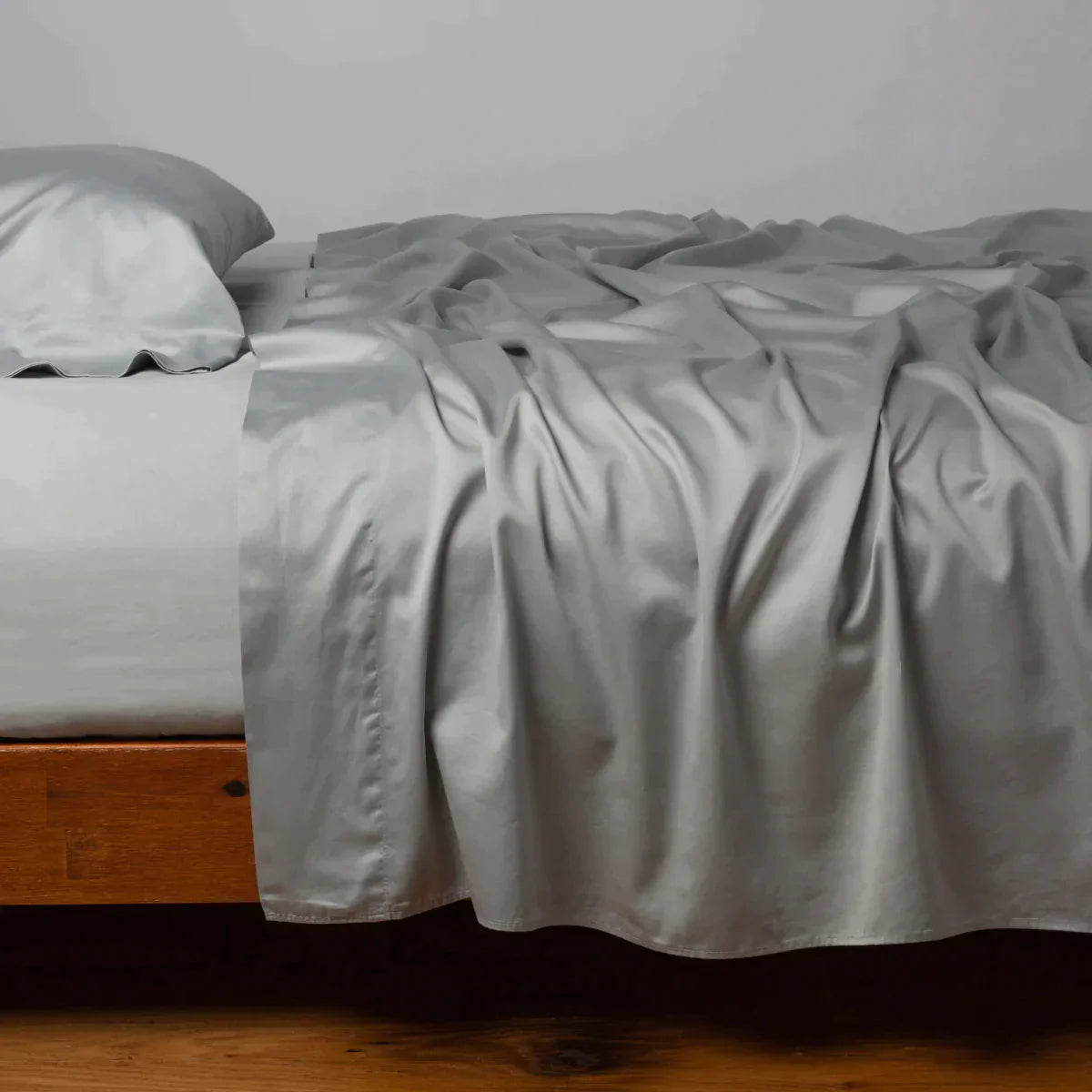 Mineral: Cotton sateen flat sheet, shown with matching fitted sheet and sleeping pillow - side view.