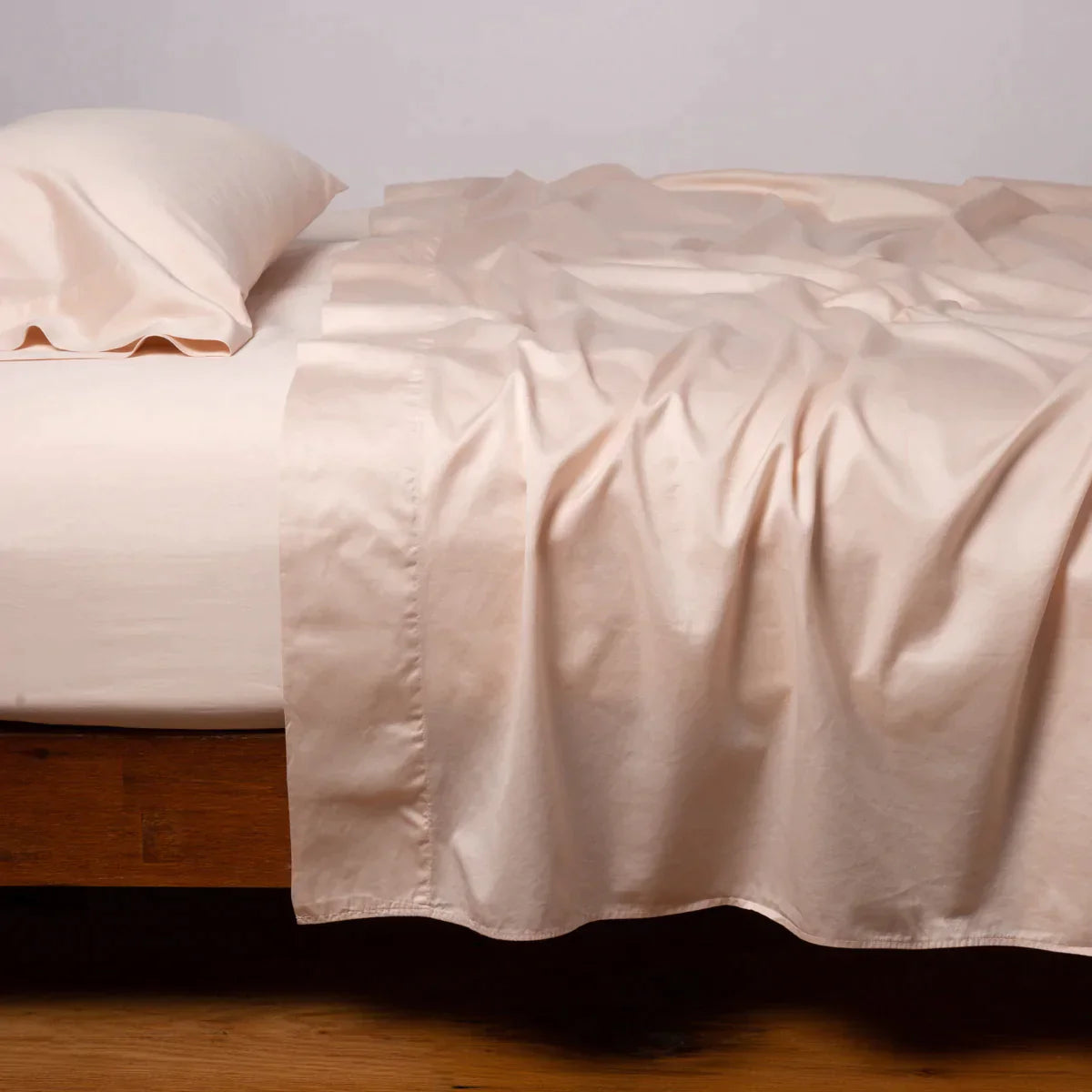 Pearl: Cotton sateen flat sheet, shown with matching fitted sheet and sleeping pillow - side view.