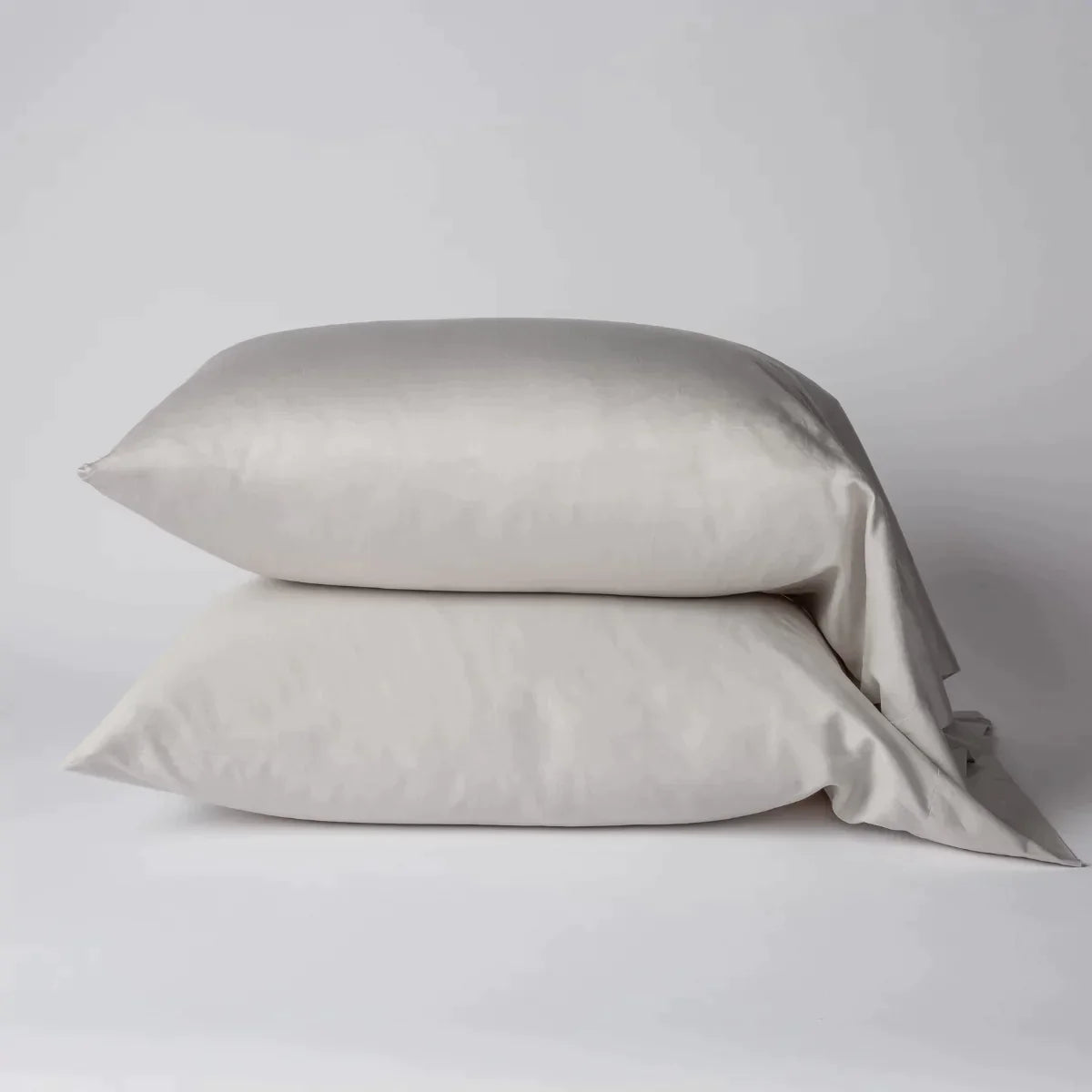 Sterling: Two cotton sateen sleeping pillows, stacked neatly against a white backdrop - side view.