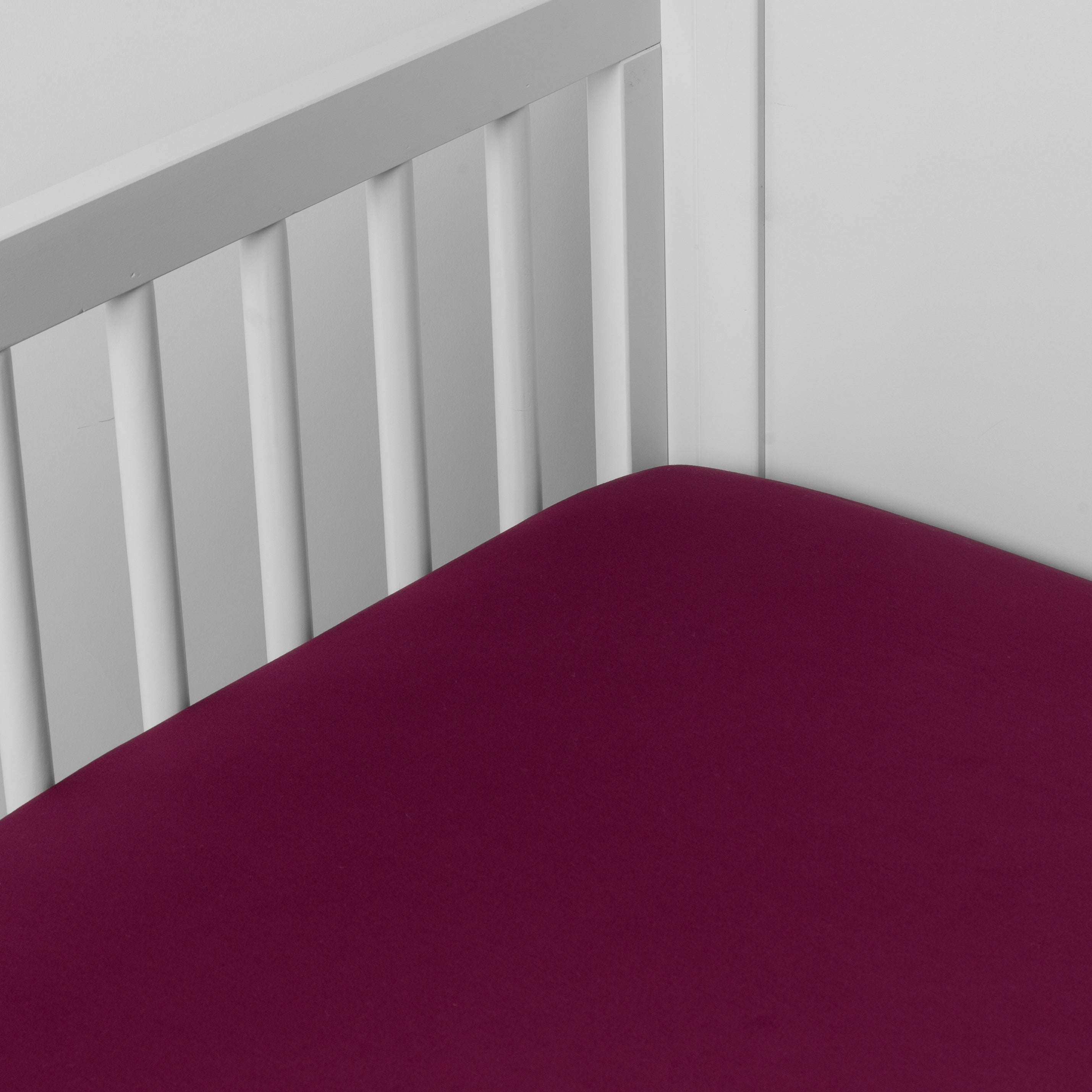 Fig: Cotton sateen crib sheet shown from a slight overhead angle into  an inside corner of a crib. 
