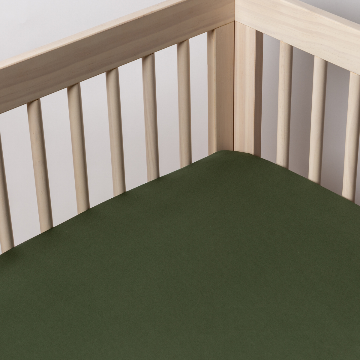 Juniper: a cotton sateen crib sheet shot into the inside corner of a natural wood crib.