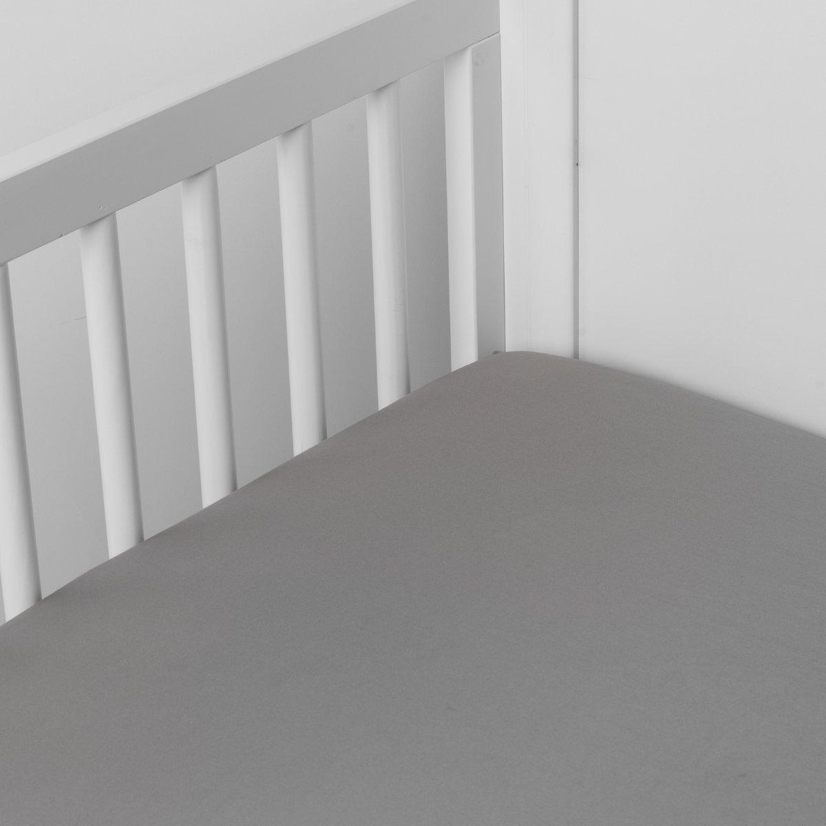 Moonlight: Cotton sateen crib sheet shown from a slight overhead angle into  an inside corner of a crib. 