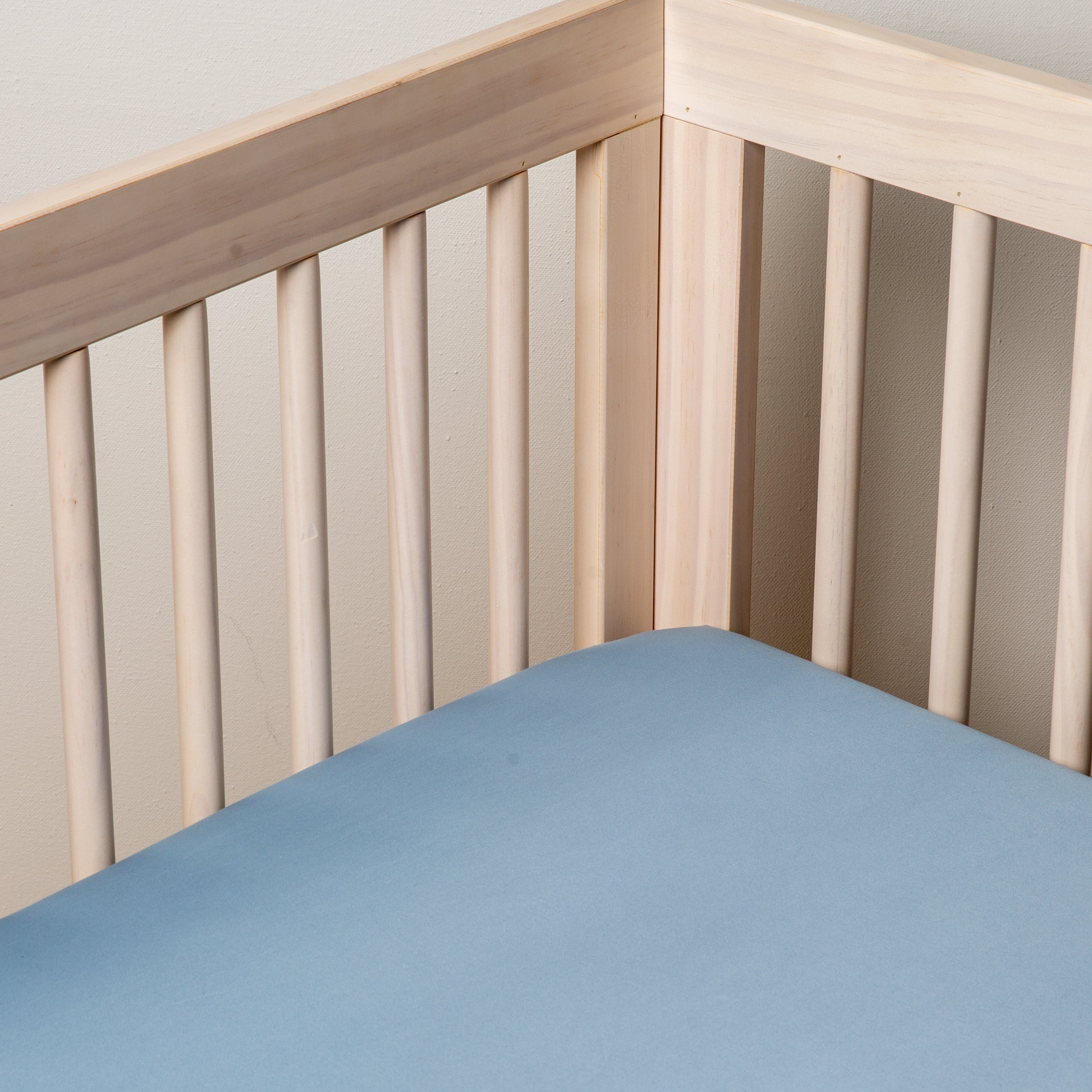 Tahoe Blue: Cotton sateen crib sheet shown from a slight overhead angle into  an inside corner of a crib. 