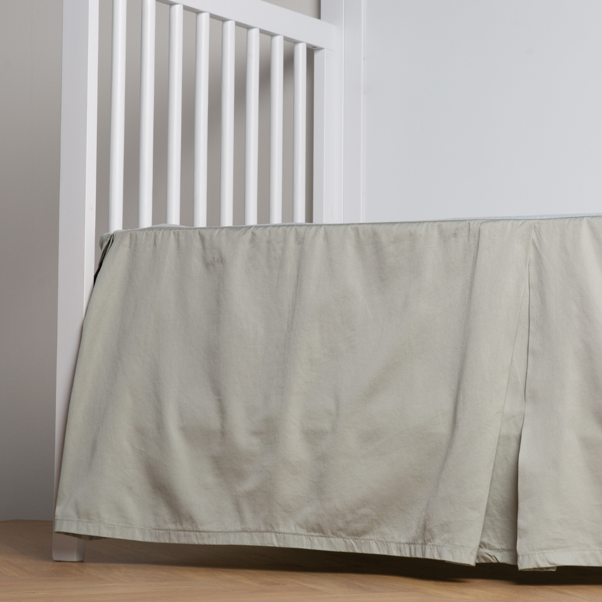Eucalyptus:  cotton sateen cribi skirt with a center pleat shown straight on from a slight angle in a crib without a crib mattress. 