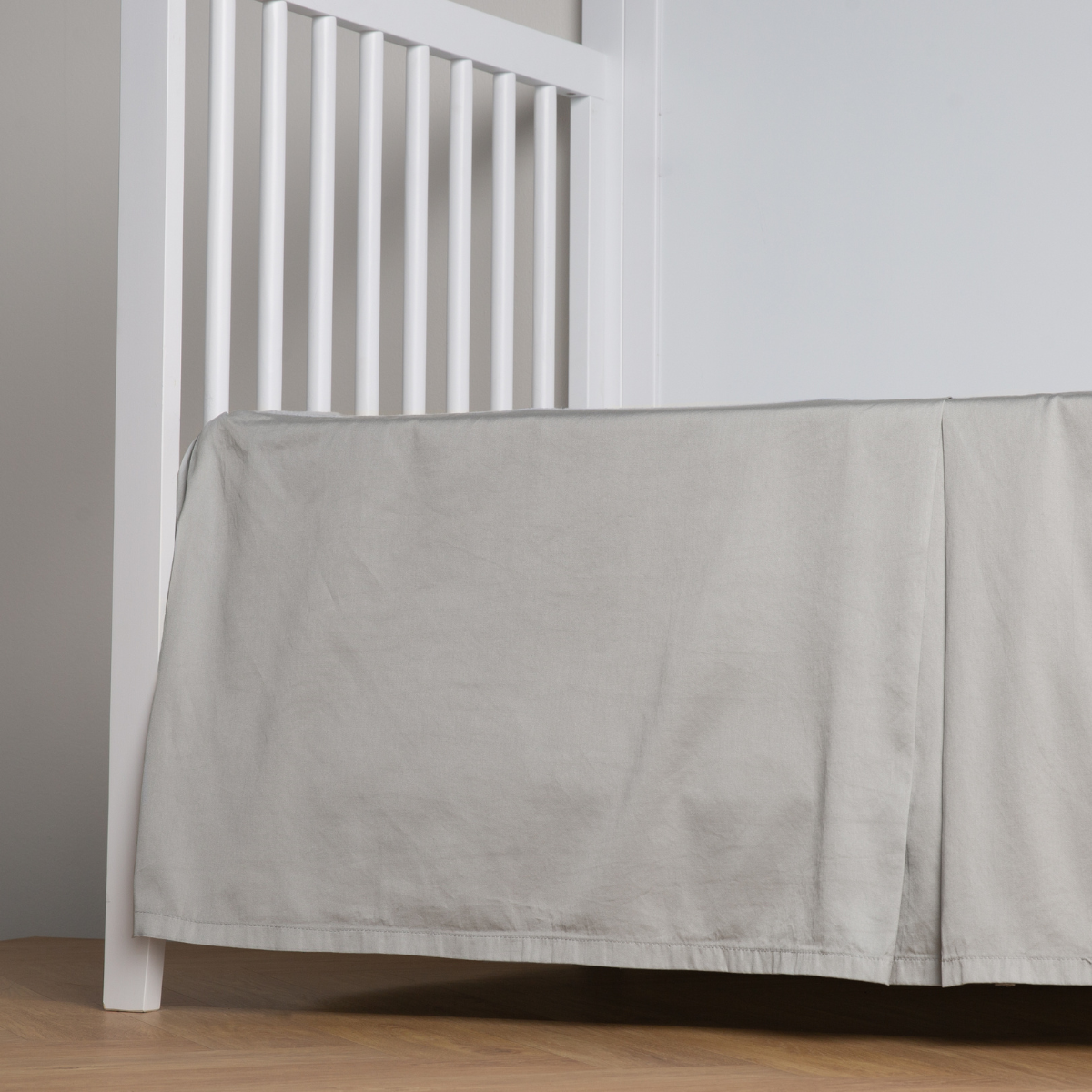 Mineral:  cotton sateen cribi skirt with a center pleat shown straight on from a slight angle in a crib without a crib mattress. 