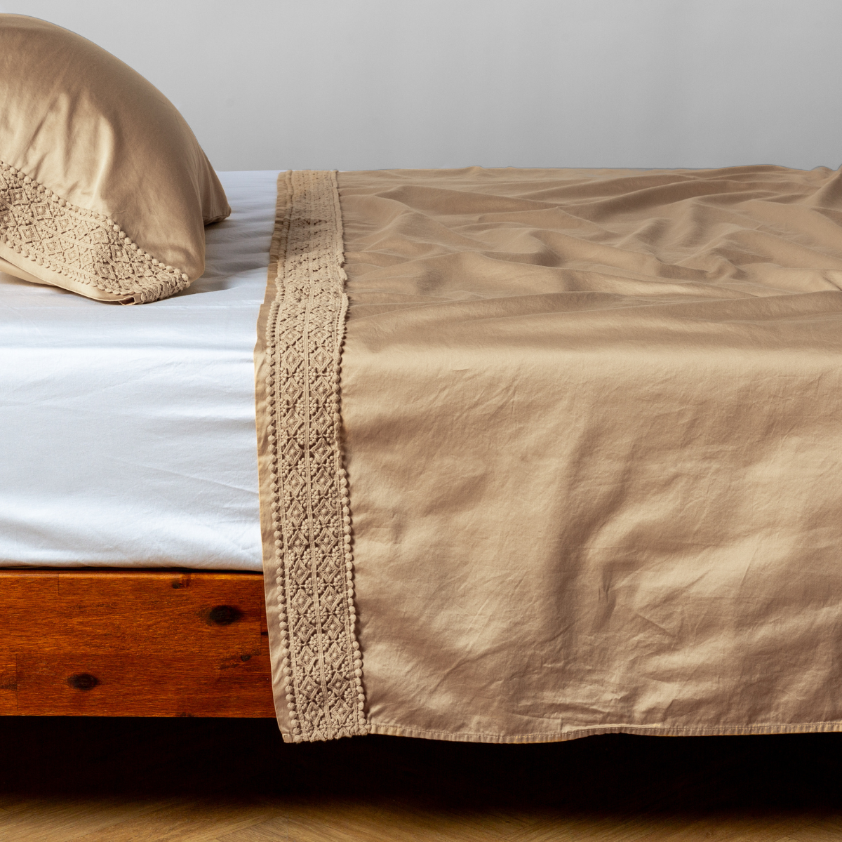 Matching lace trimmed cotton sateen flat sheet and pillowcase shown with a winter white fitted sheet - side view. 