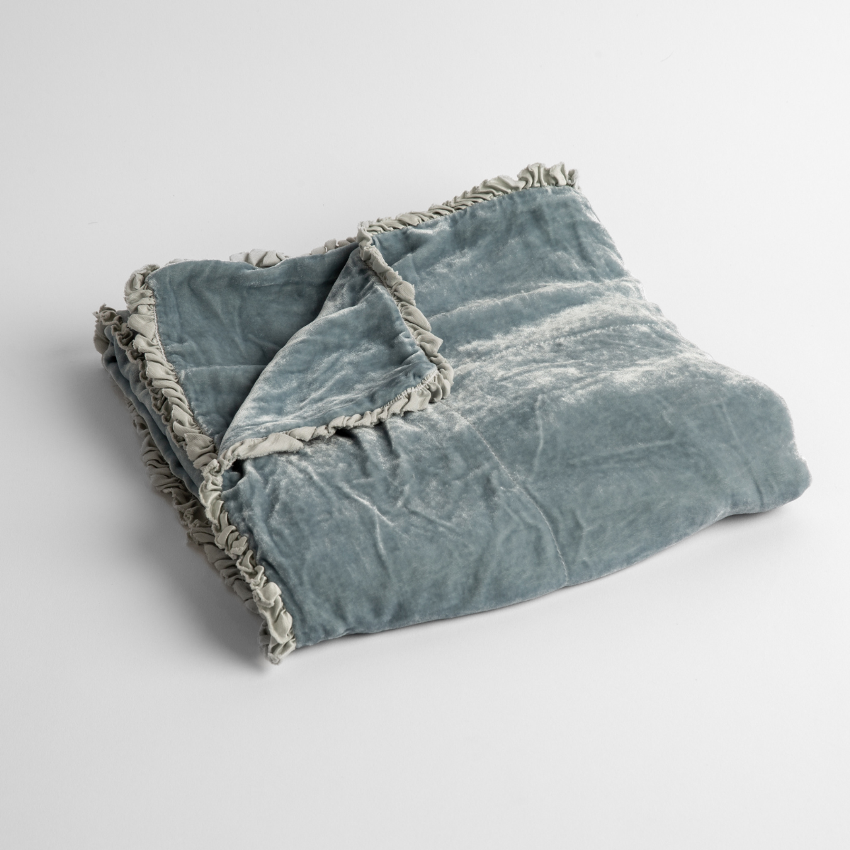 Cloud:  silk velvet baby blanket with charmeuse trim shown slightly overhead with a corner folded back to show trim detail against a white background. 