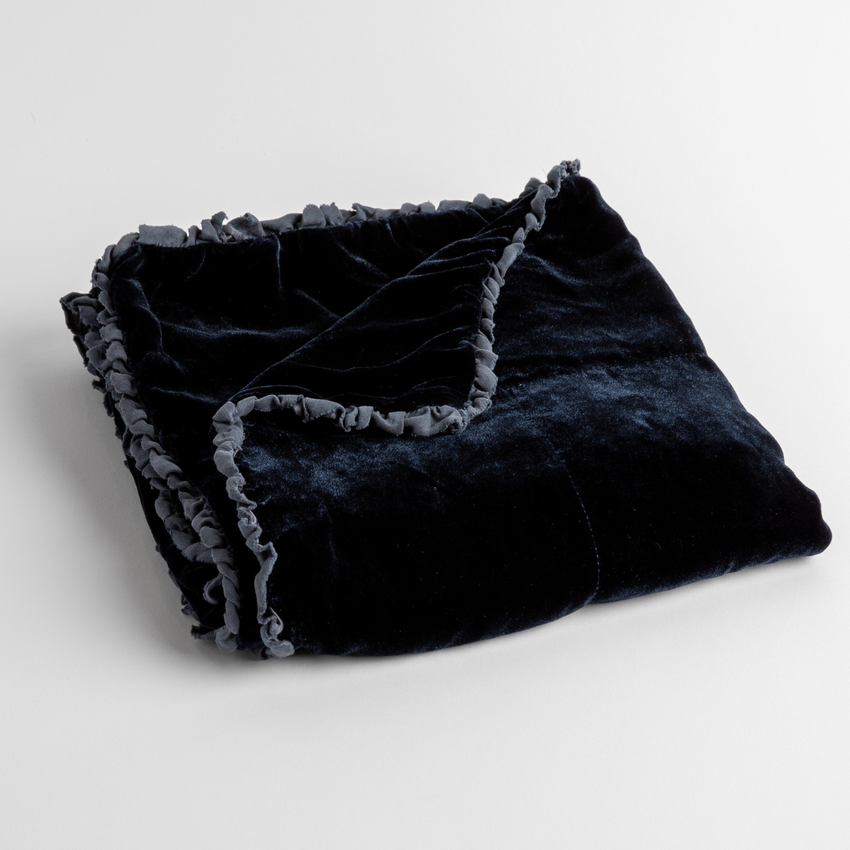 Midnight:  silk velvet baby blanket with charmeuse trim shown slightly overhead with a corner folded back to show trim detail against a white background. 