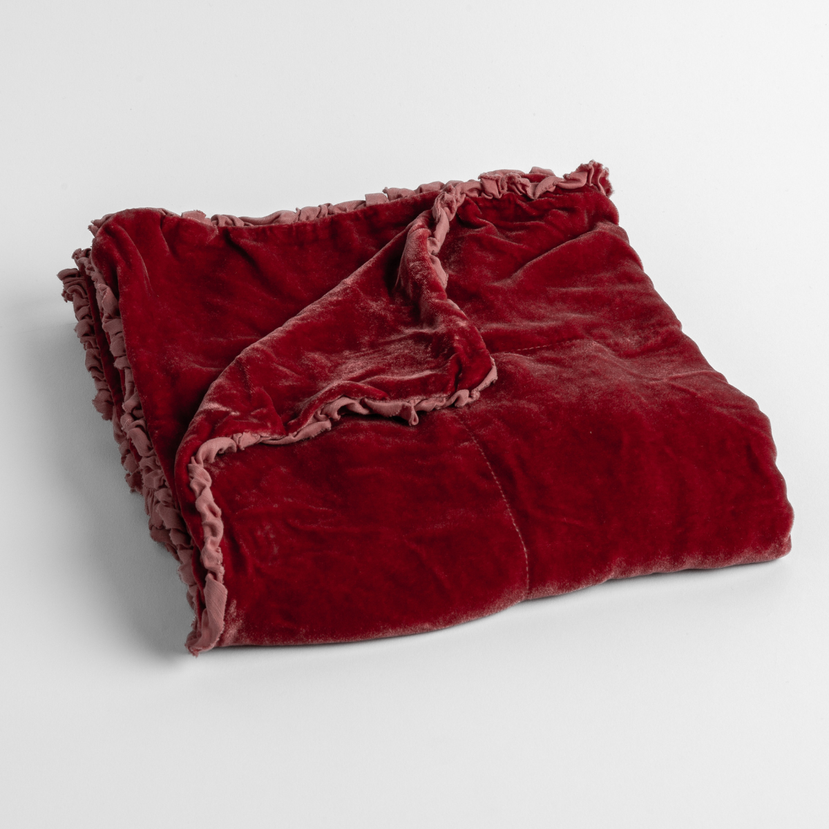 Poppy:  silk velvet baby blanket with charmeuse trim shown slightly overhead with a corner folded back to show trim detail against a white background. 