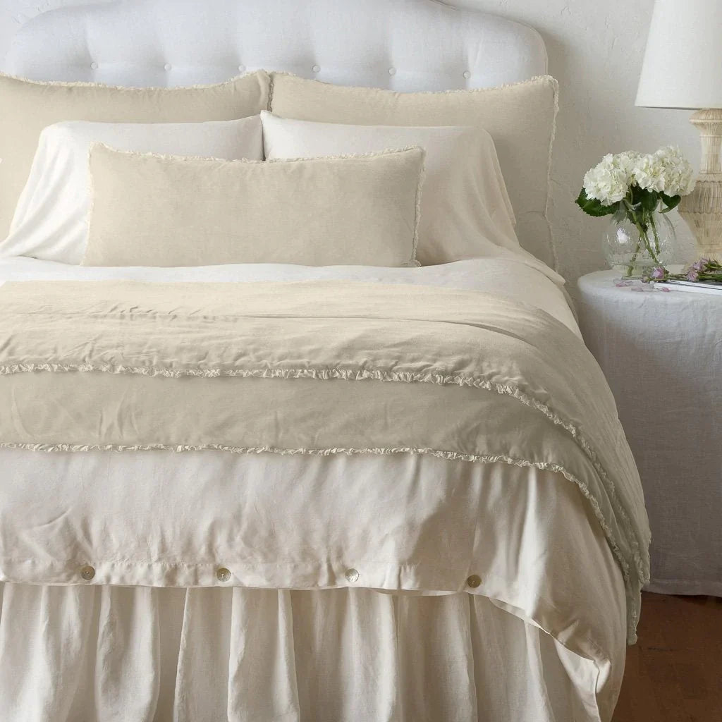 Parchment: Silk velvet shams with a petite ruffle on a monochromatic bed, stacked behind sleeping and throw pillows - view from end of bed.