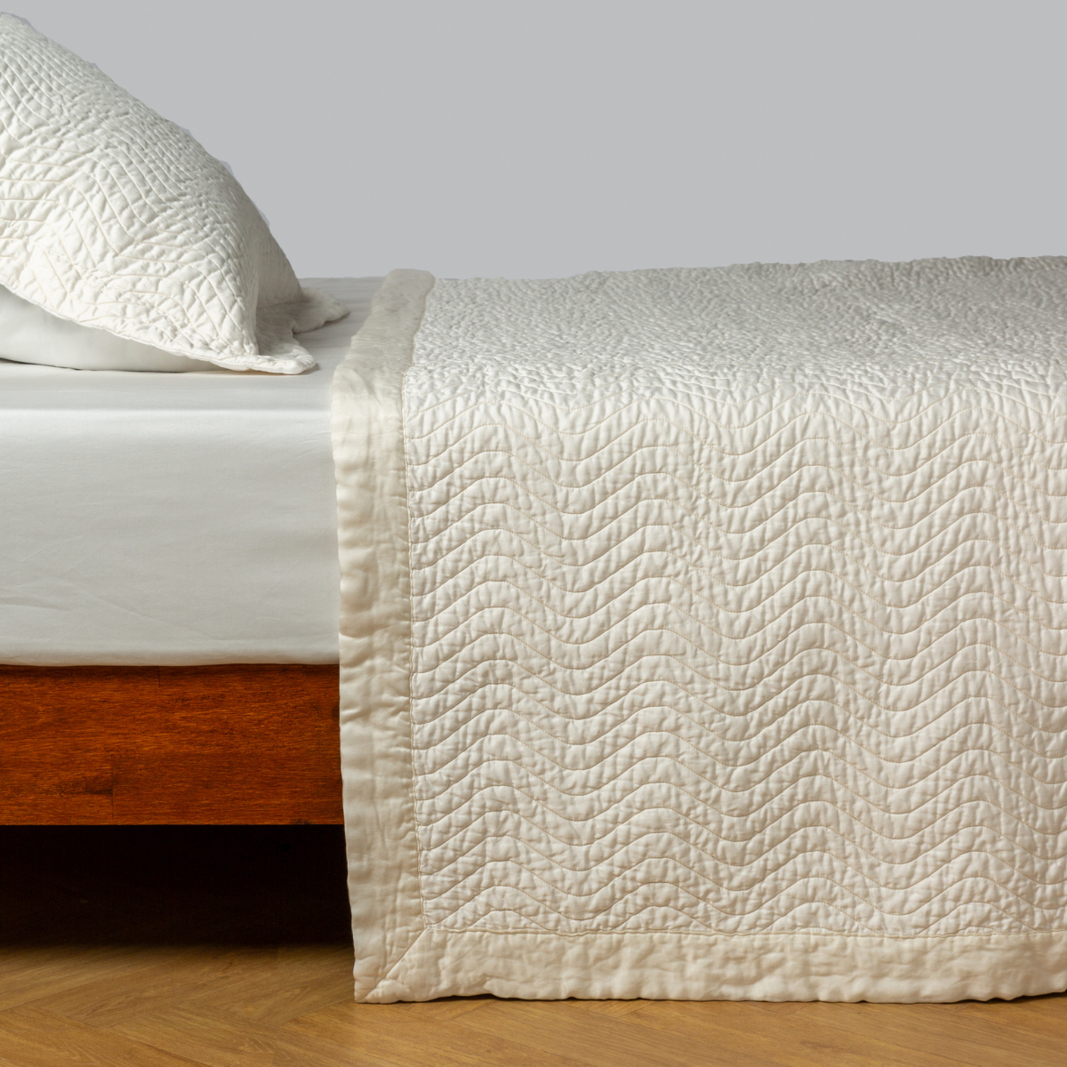 Winter White: quilted cotton sateen coverlet with matching sham on a winter white fitted sheet - side view. 