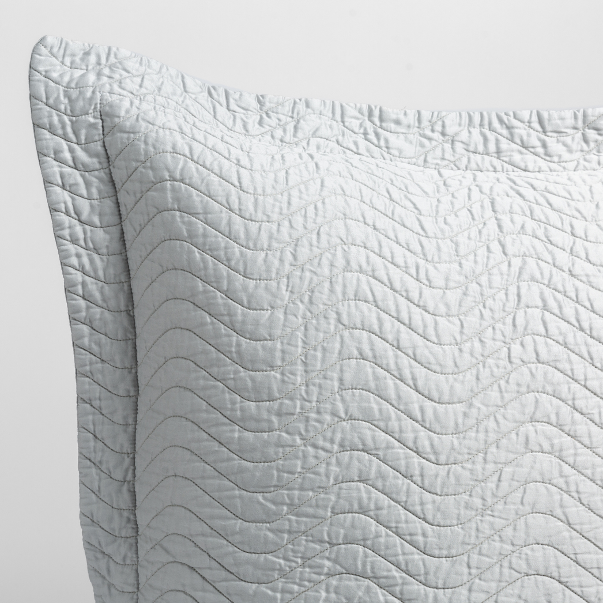 Cloud: close up of the corner of a quilted cotton sateen pillow sham - shot against a white background. 