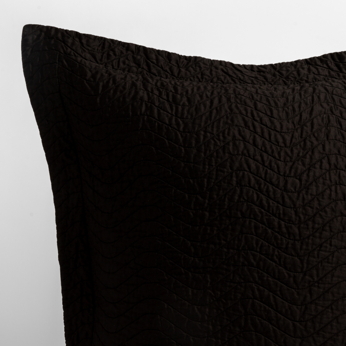 Corvino: close up of the corner of a quilted cotton sateen pillow sham - shot against a white background. 