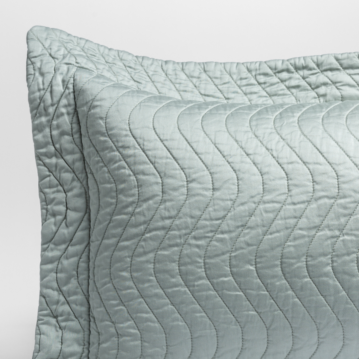 Eucalyptus: a close up of a pillow corner showing the flange framing quilted cotton sateen shot against a white background. 