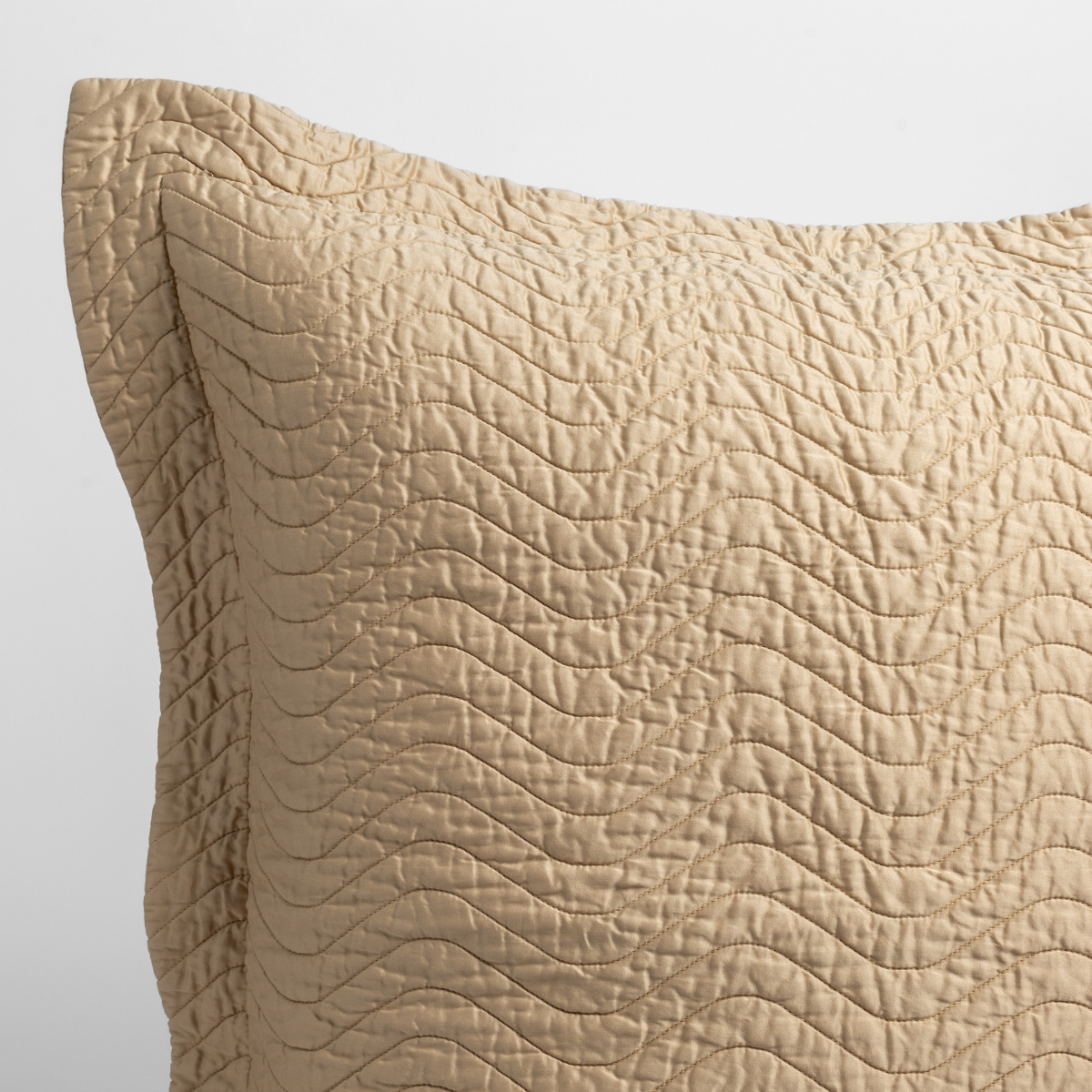 Honeycomb: close up of the corner of a quilted cotton sateen pillow sham - shot against a white background. 
