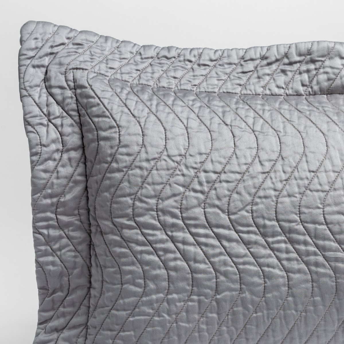 Moonlight: close up of the corner of a quilted cotton sateen pillow sham - shot against a white background. 